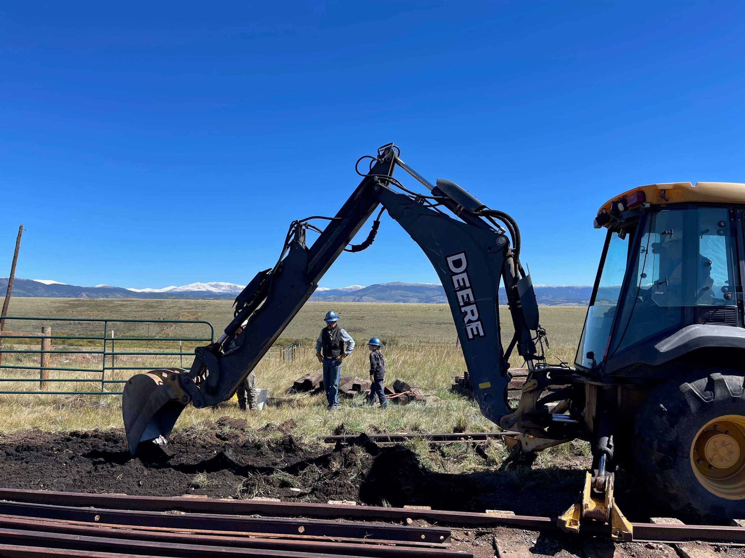  Volunteers Aaron and his son Takoda watch the backhoe level the dirt for the new switch.  