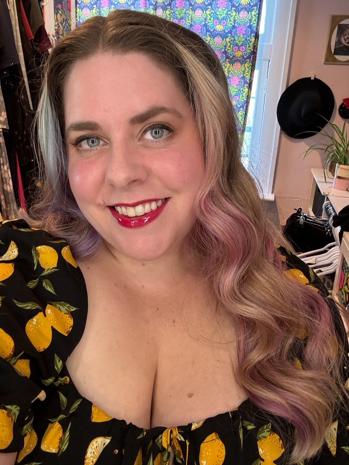 Blue-eyed white woman with long hair wearing a black dress with lemon print shown from the chest up