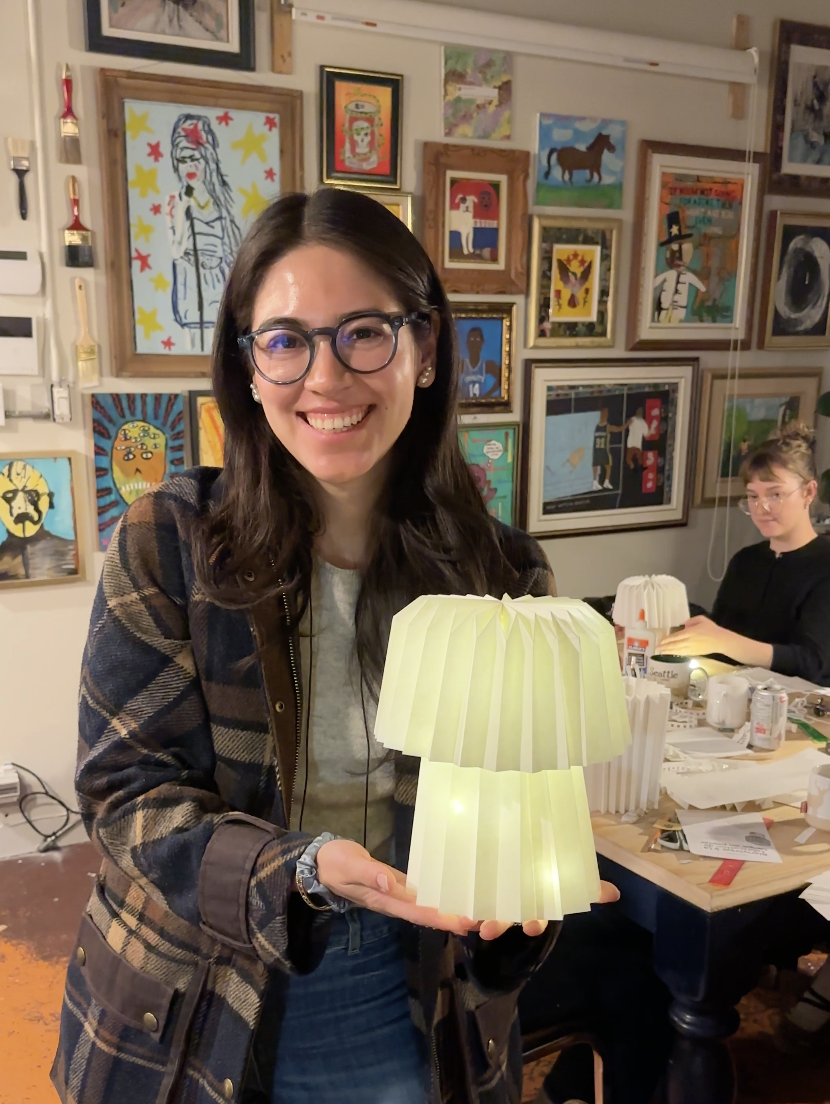 A woman shows off her paper lamp creation.