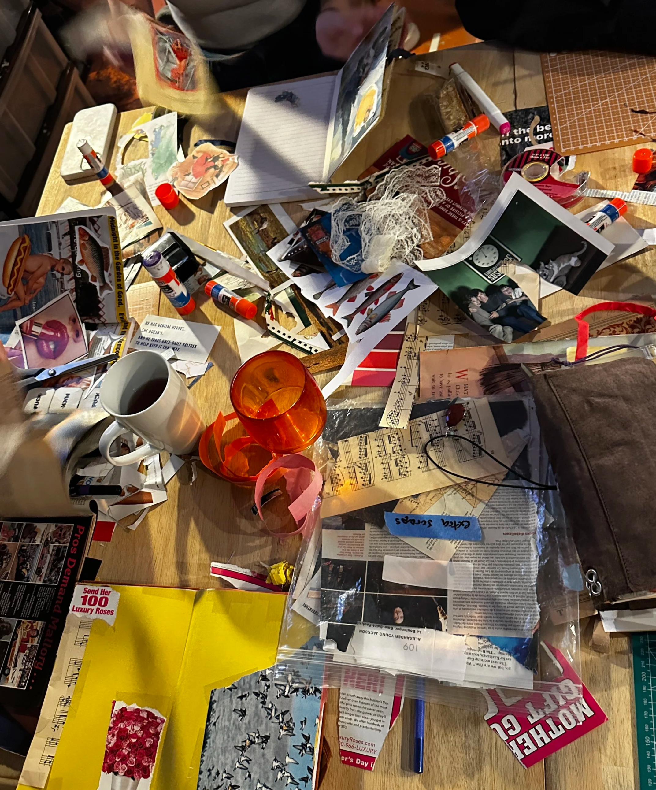 A table full of collage supplies, with hands busy working