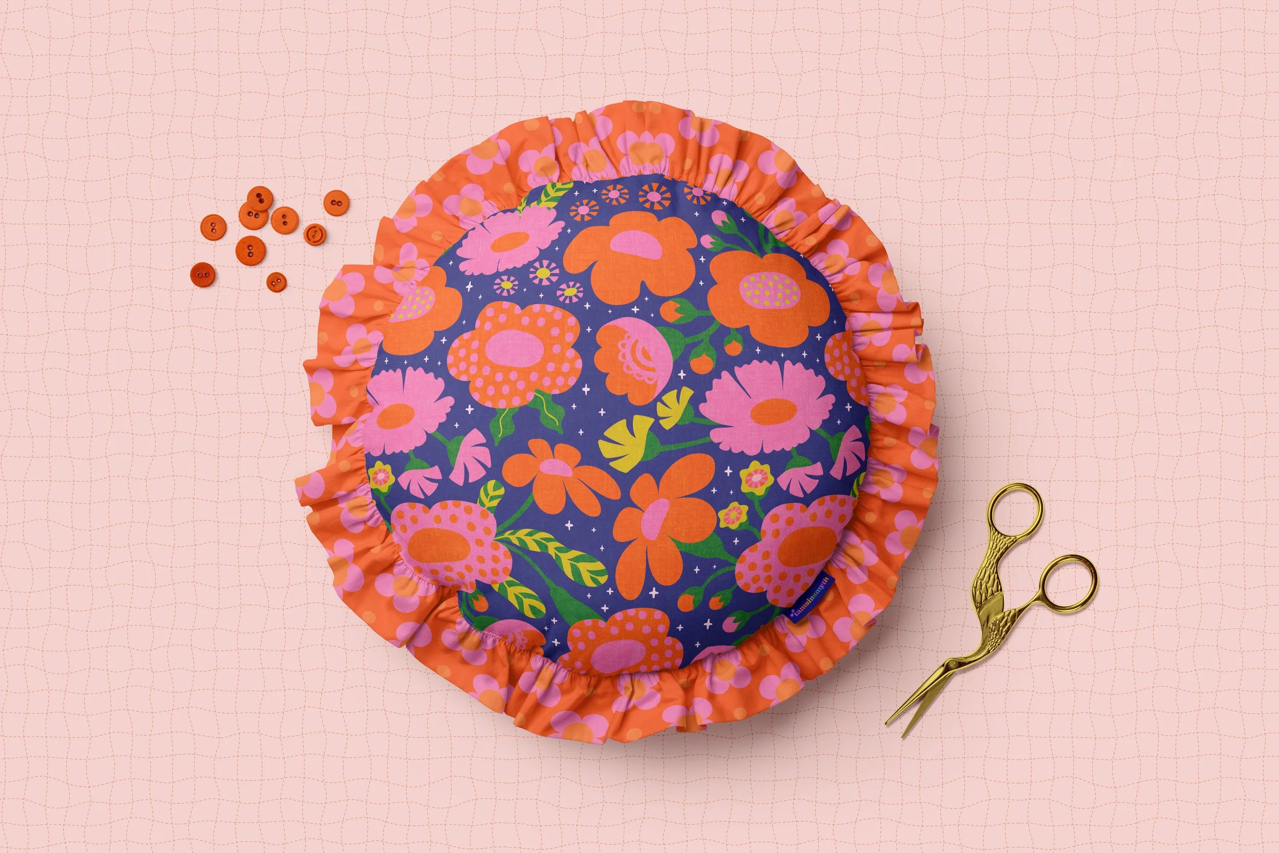 a pillow with a ruffled edge and a bold pink and red flower pattern