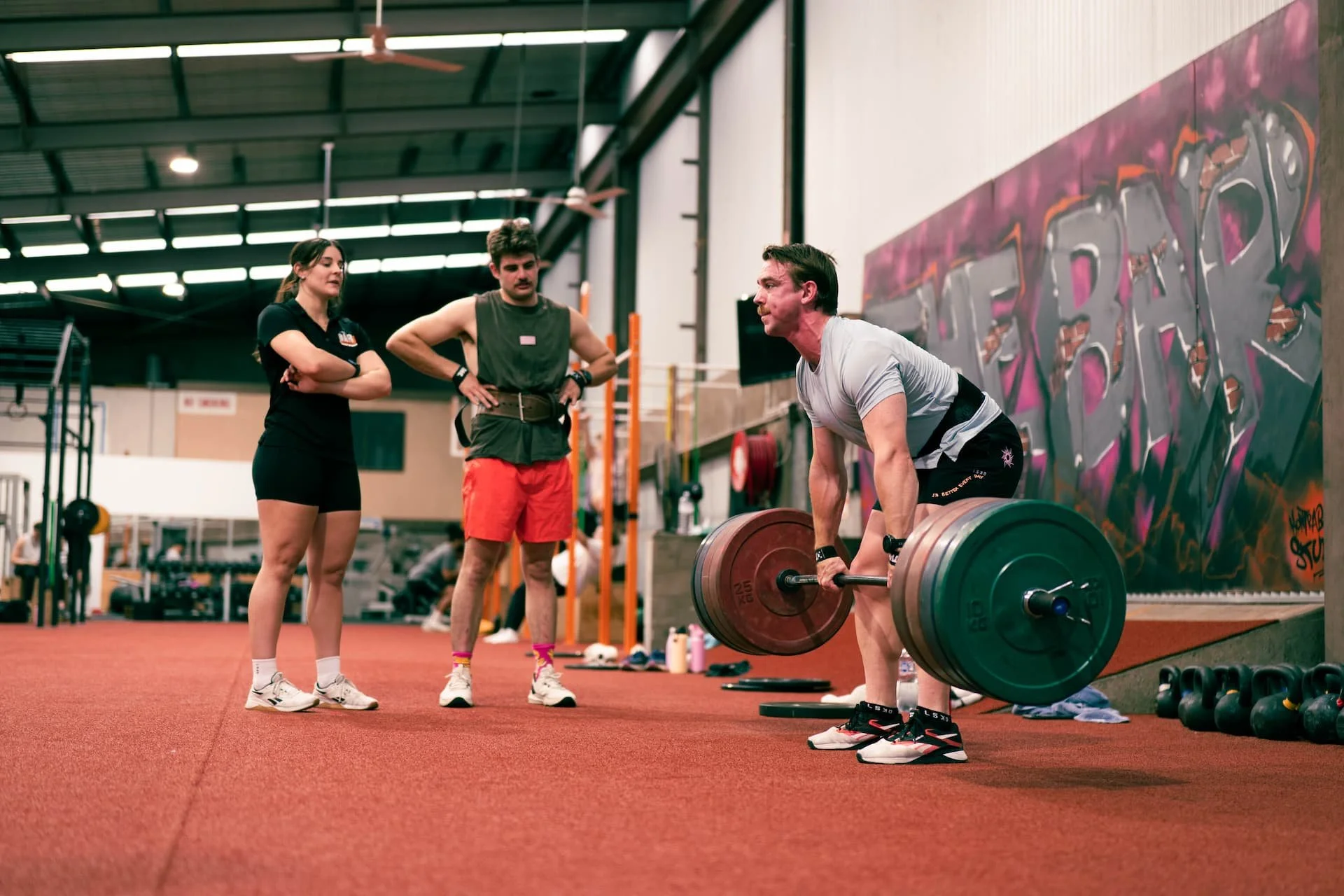 female member of the bar health and fitness - performing a barbell movement in a strength group class