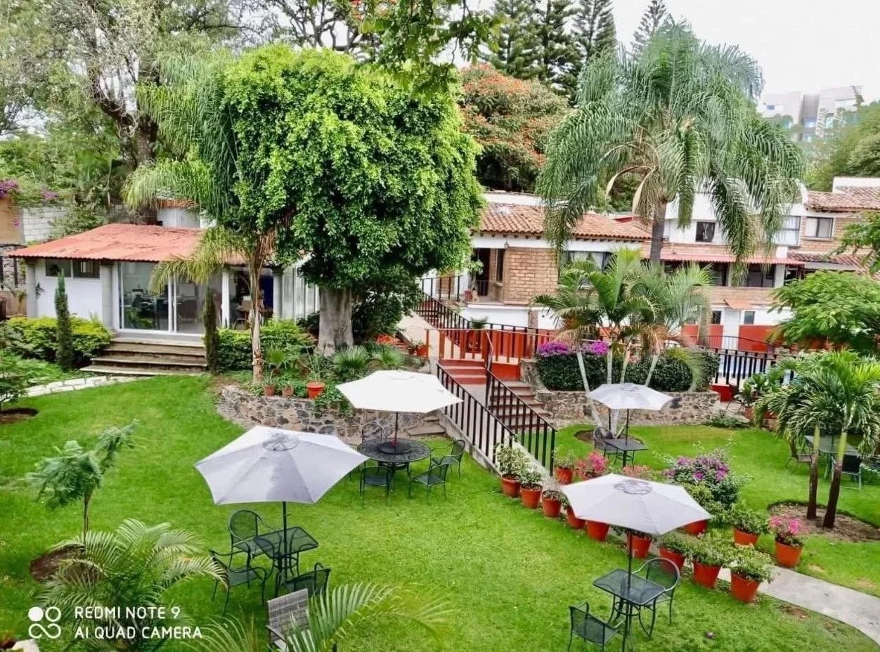 Jardín con mesas y sombrillas de la residencia Las Maravillas en Lomas de Cortés, Cuernavaca