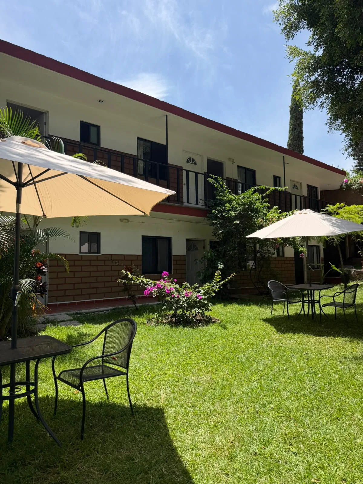 Mesas con sombrillas frente a las habitaciones y el jardín de Las Maravillas, Lomas de Cortés