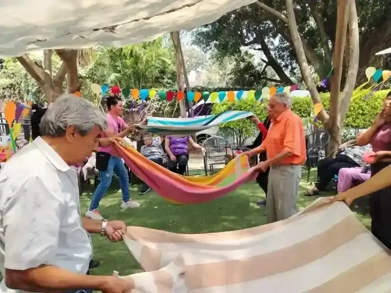 Adultos mayores participan en una actividad grupal con telas de colores en el jardín
