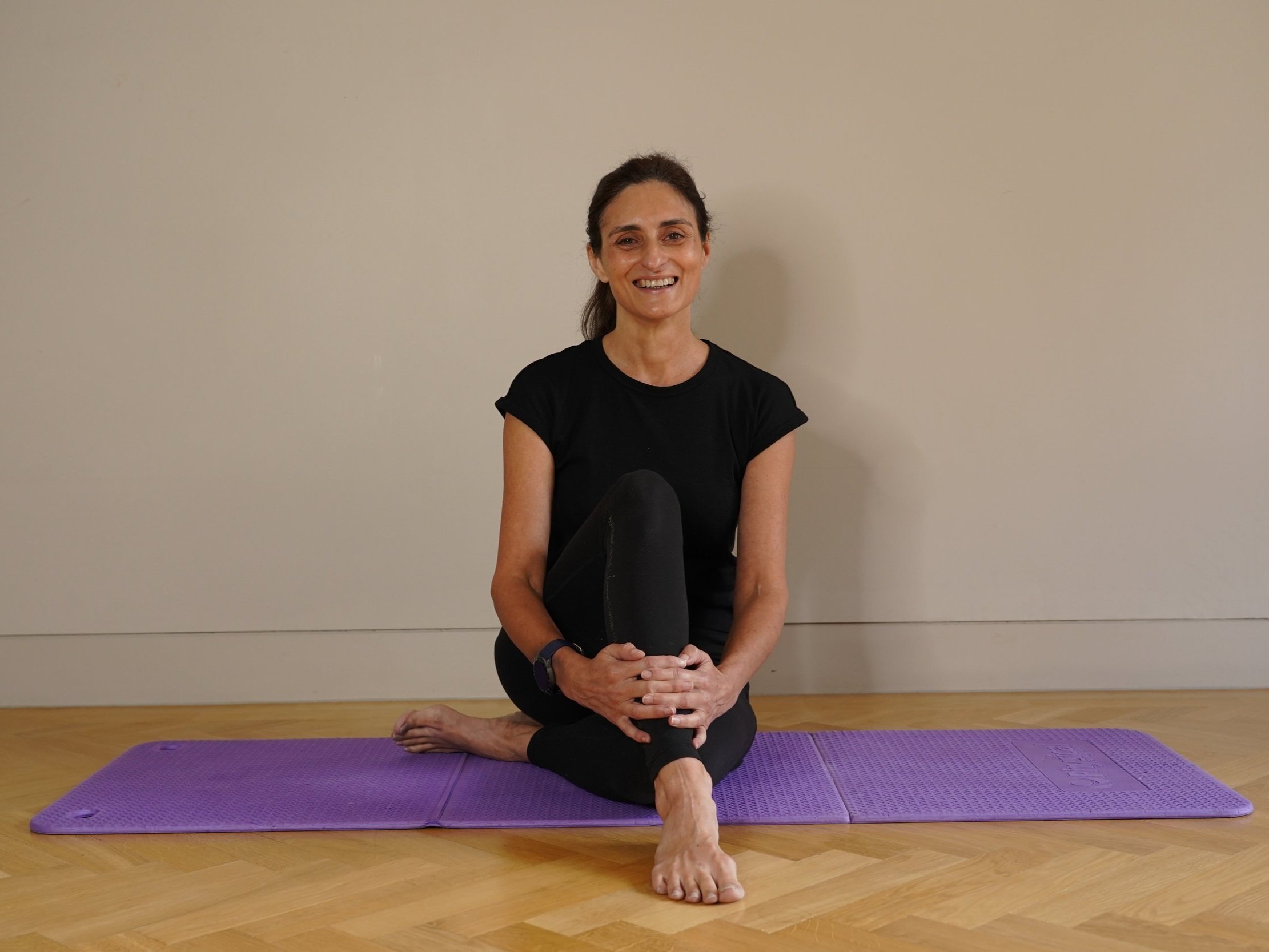 Elizabeth Lavarini, the founder of Holistic Movement, sitting on a yoga mat