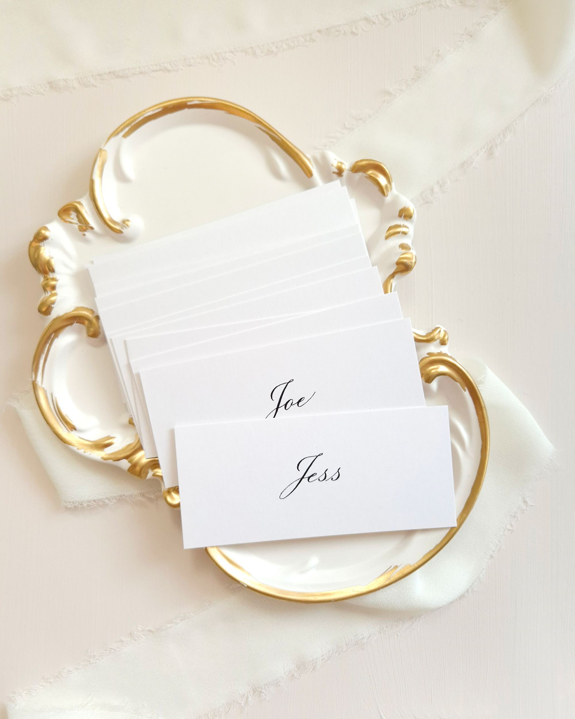 White place cards with black calligraphy names on them. The names are 'Shirley', 'Jen', 'Jamaul', and 'Jess'.