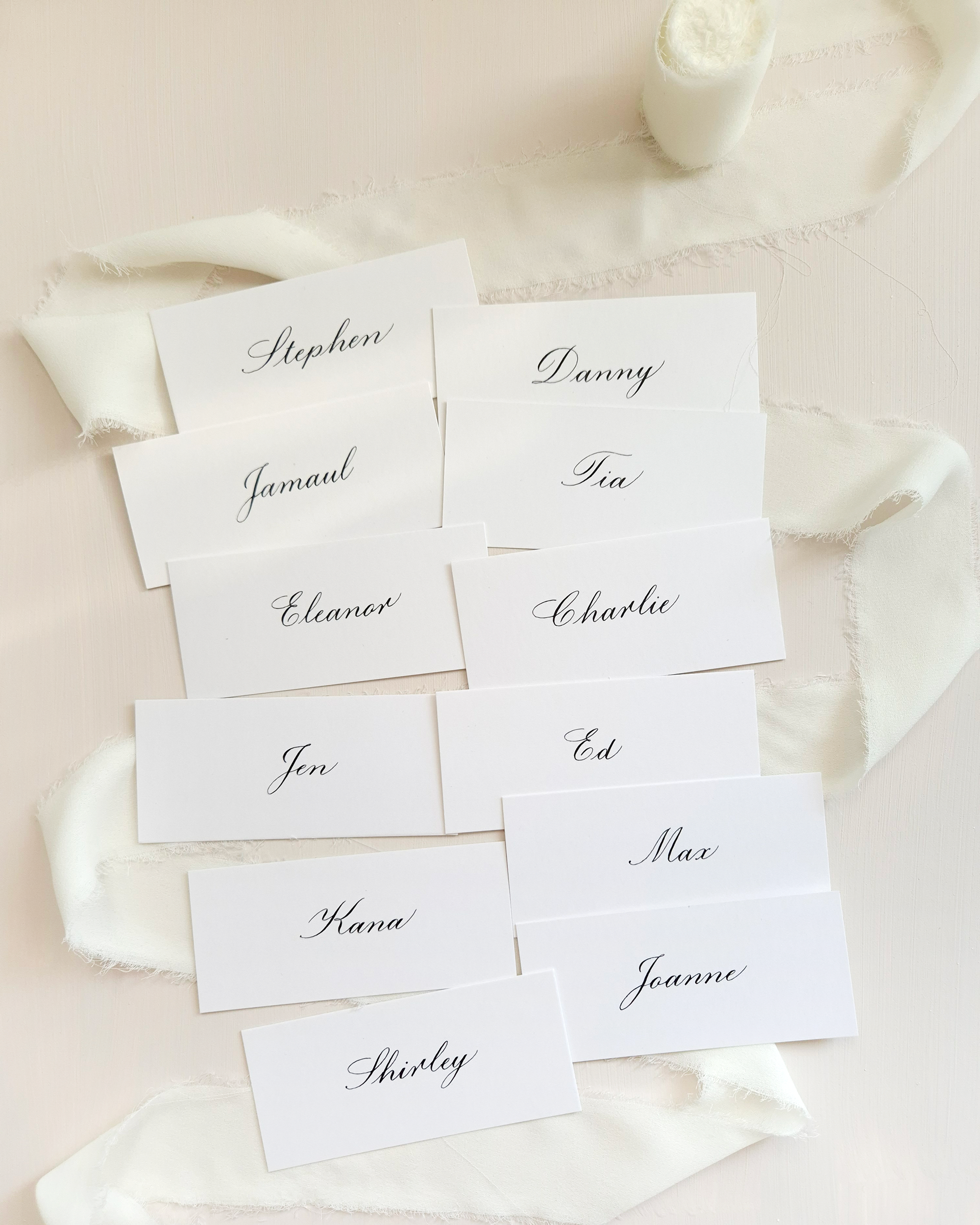 White place cards with black calligraphy names: Stephen, Danny, Jamaul, Tia, Eleanor, Charlie, Jen, Ed, Kana, Max, Joanne, Shirley.