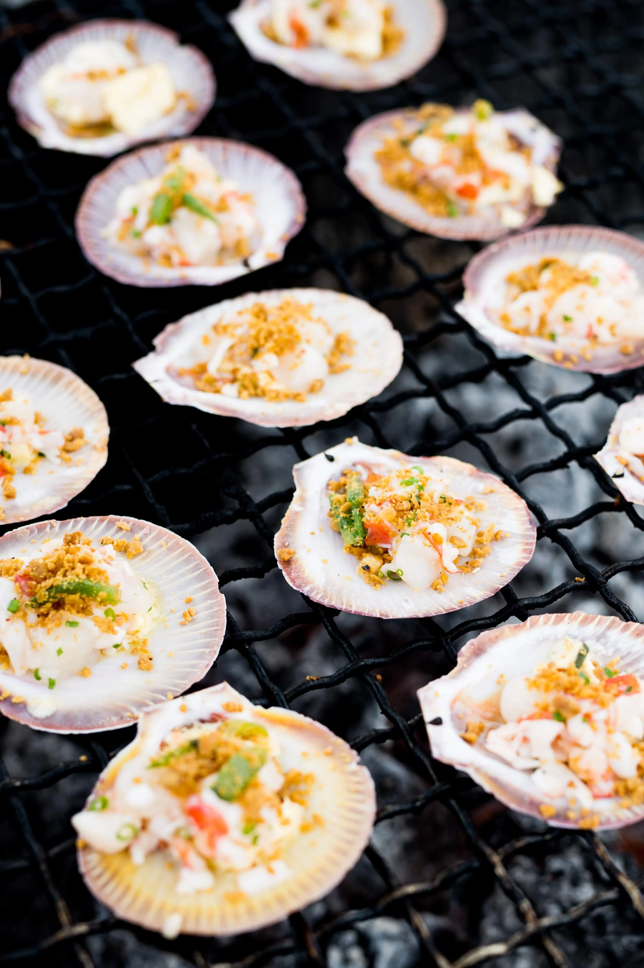 Scallops with toppings on a grill.
