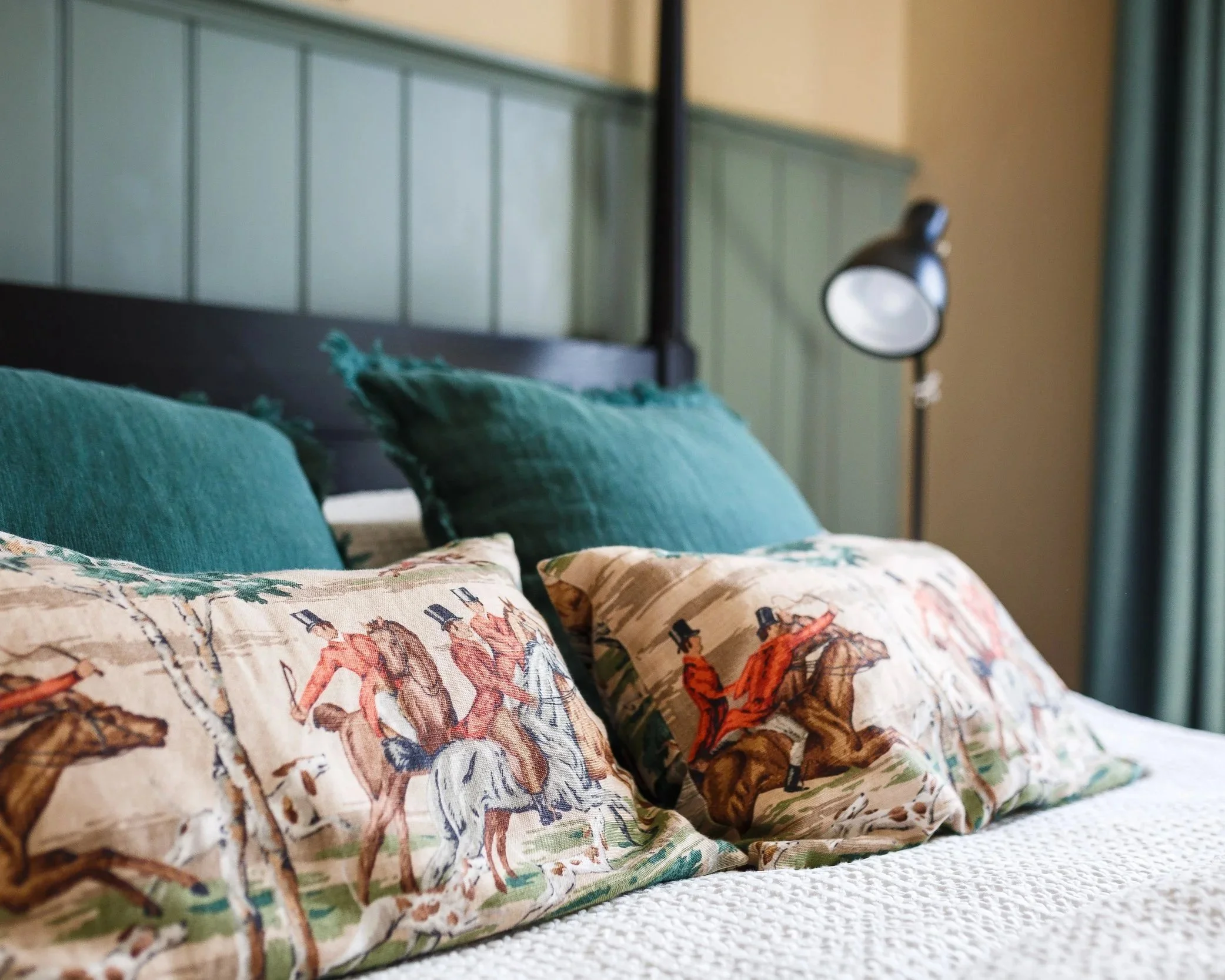 Characterful country house bedroom renovation with painted panelling, horse cushion and layered textiles, combining heritage interior design with timeless comfort for a refined period property transformation.