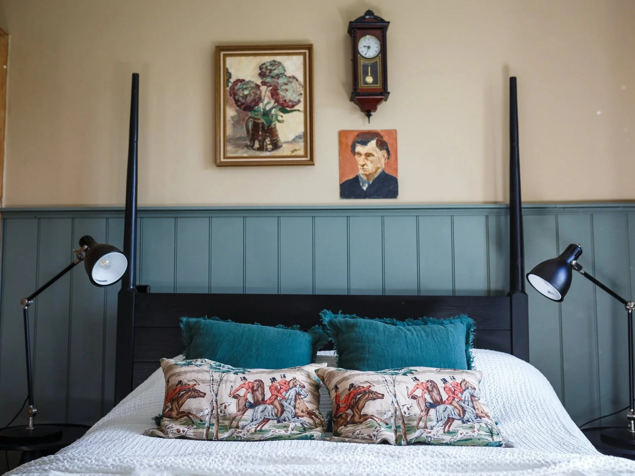 Elegant country house bedroom refurbishment blending heritage character with contemporary comfort. Panelled walls, vintage artwork, layered textiles and tailored lighting create a timeless rural interior designed for modern living.