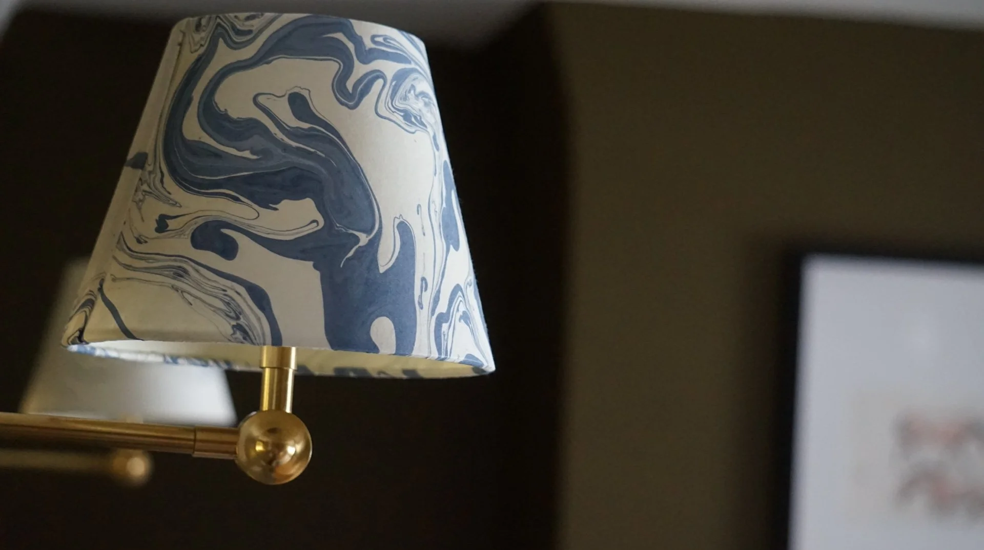 Brass wall light with marbled shade in a Liverpool heritage renovation blending Victorian detailing with North Wales inspired tones.