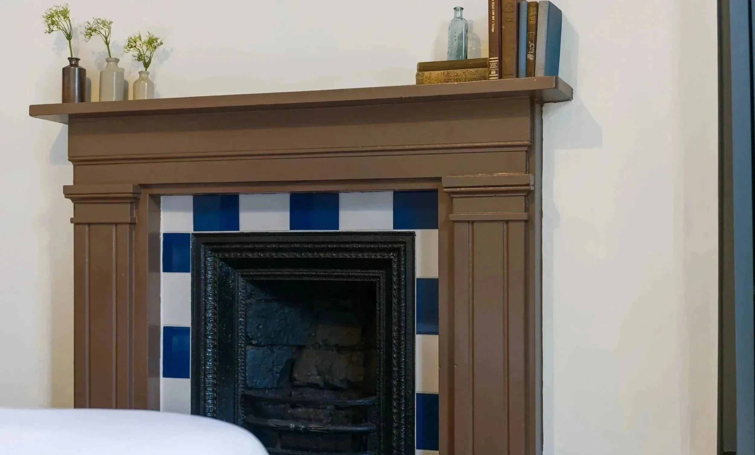 Restored Victorian fireplace in a Liverpool heritage renovation featuring original timber mantel and blue tiled surround.