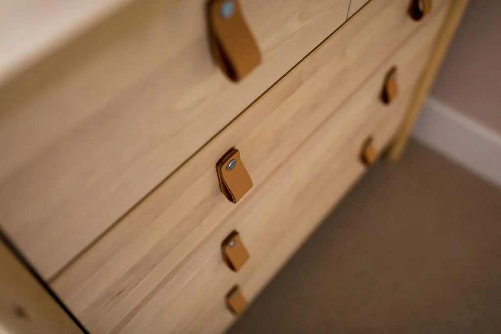 Contemporary show home furniture detail by Stiwdio Interior Design featuring natural wood drawers with leather pull handles for refined, modern interior styling.