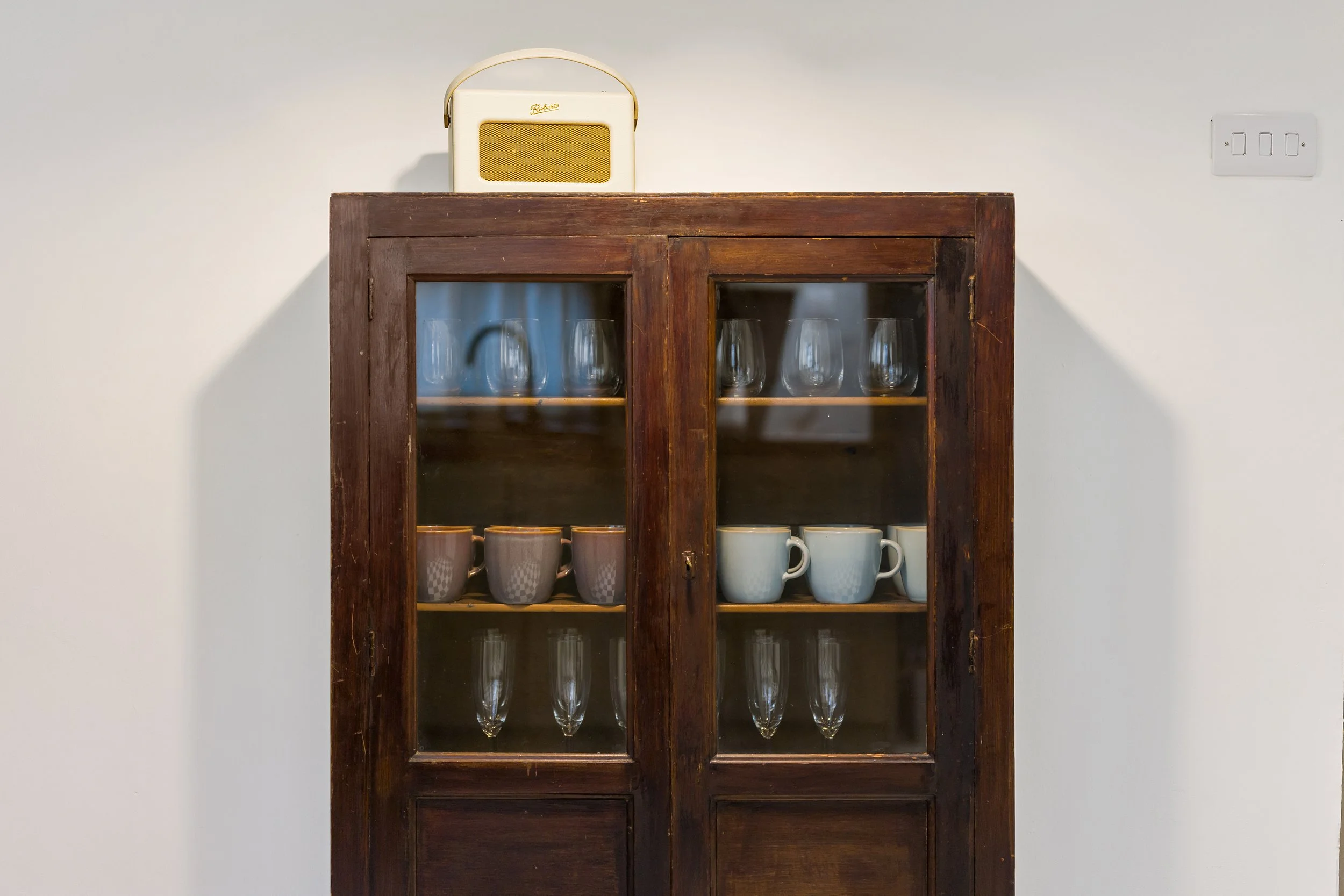 Heritage kitchen with checkerboard floor, vintage wooden cabinet, pendant light and taupe door, part of Stiwdio Interior Design’s Liverpool Georgian renovation.