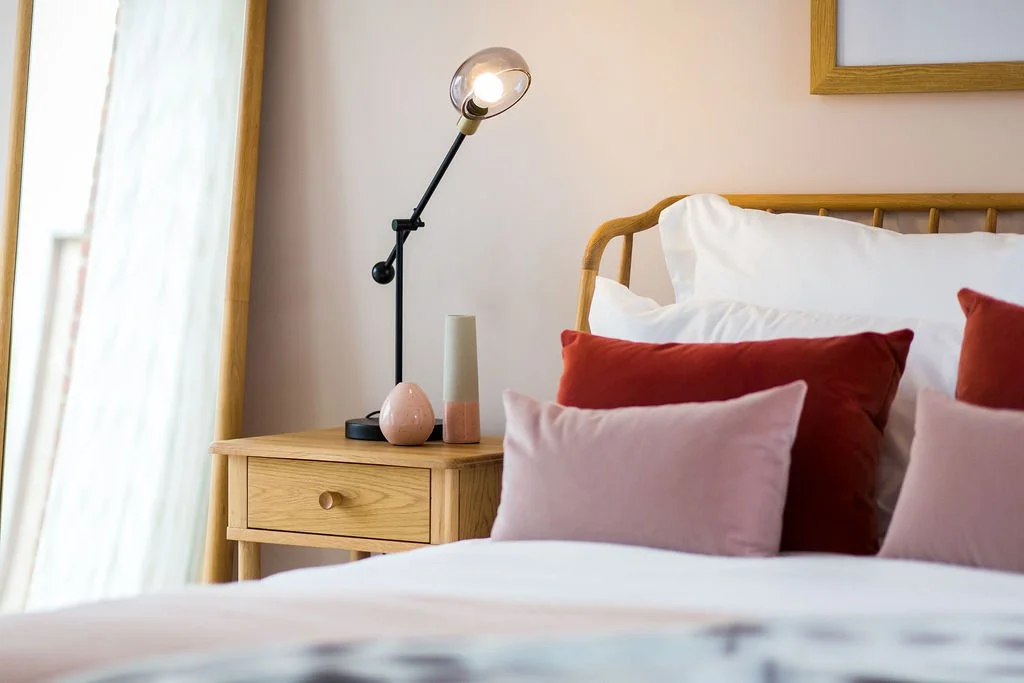 Show home bedroom in pink and red tones, scandi style with soft woods and sheer curtains