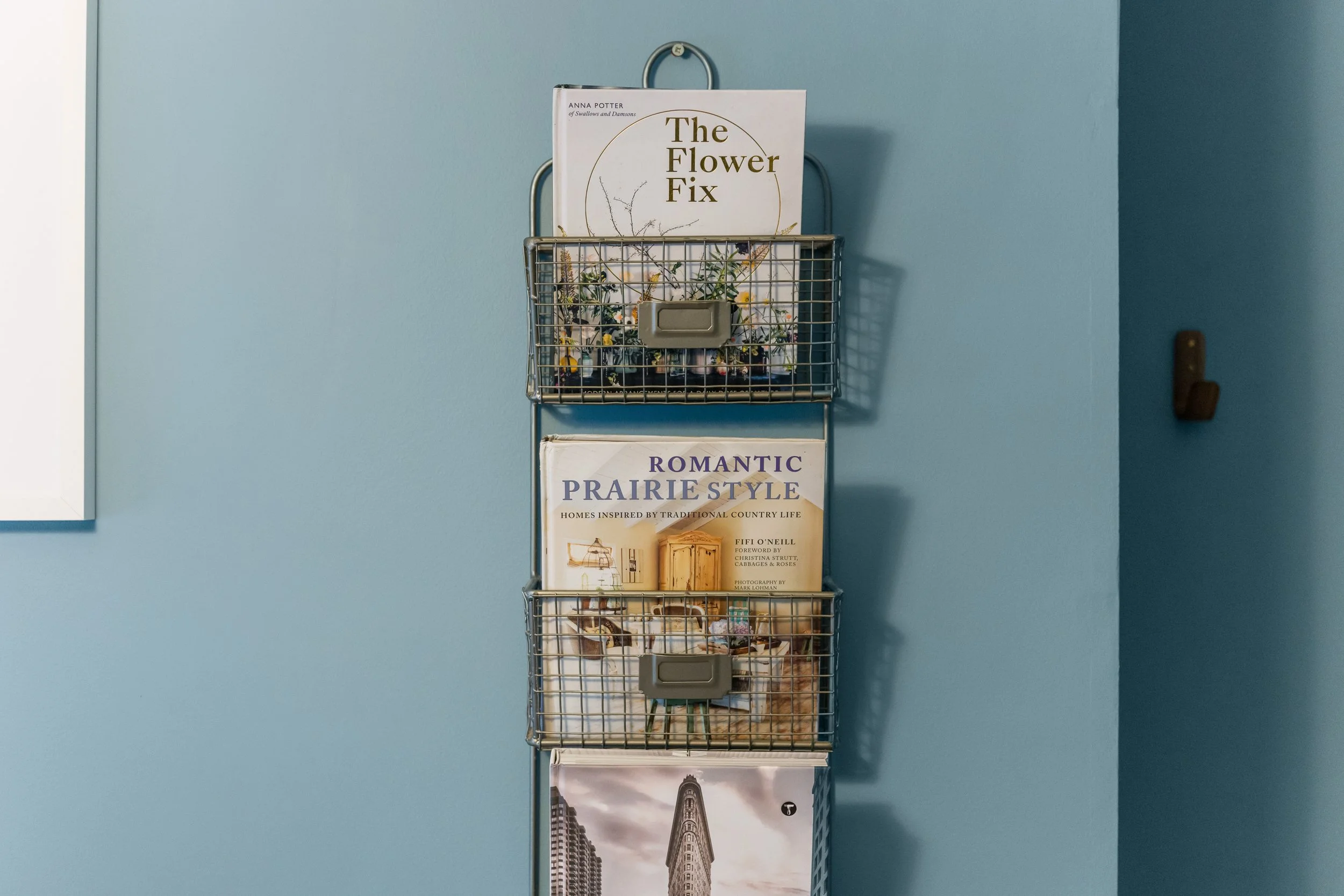 Magazines in metal magazine rack on blue wall in liverpool Georgian townhouse