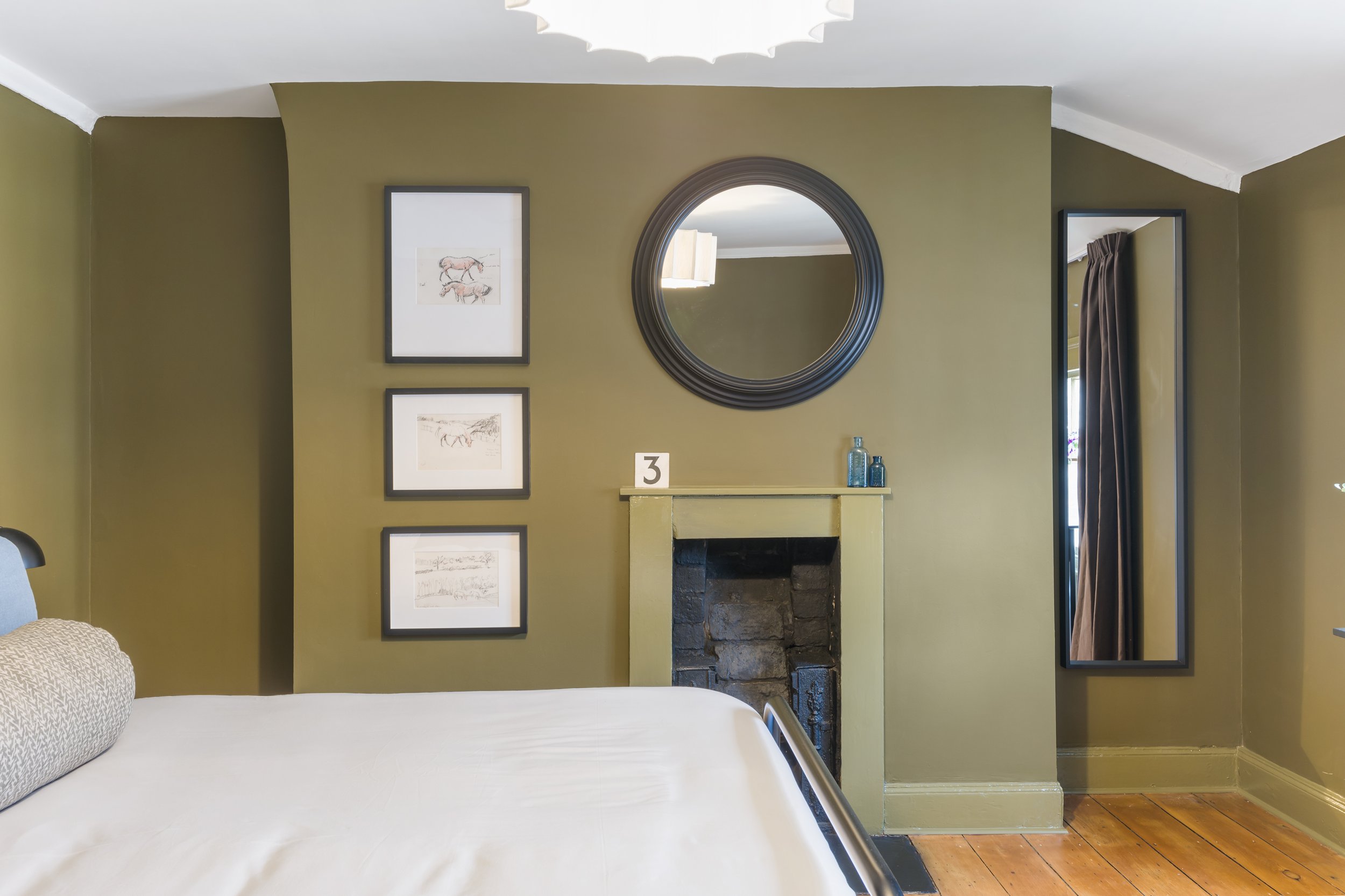 Minimalist interior wall detail featuring a small vintage black-and-white photograph centered within a large, empty dark wood picture frame. Soft neutral wall tones and clean lines create a refined, understated aesthetic that highlights nostalgic art