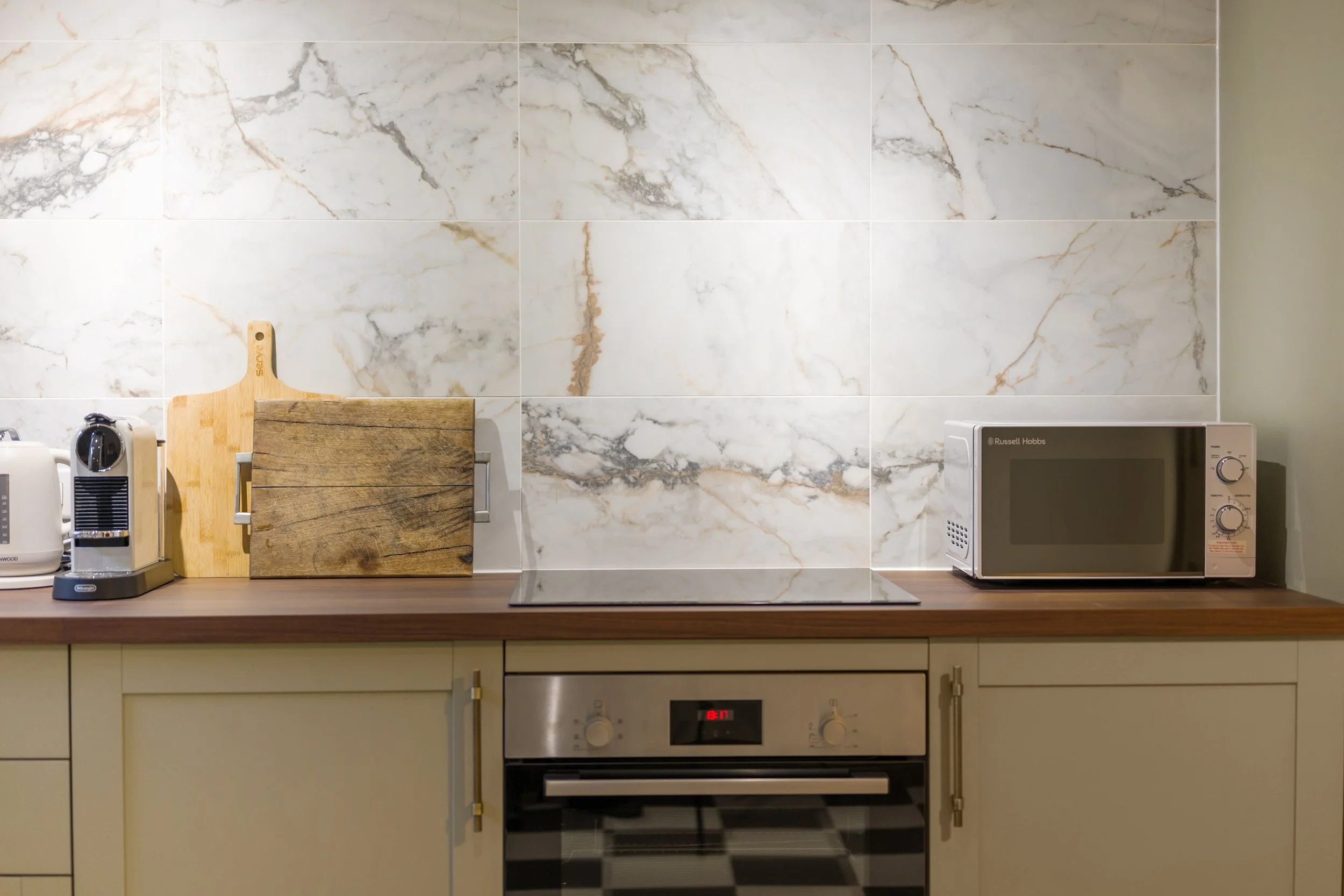 Stylish kitchen in a Georgian Quarter Liverpool holiday let featuring marble-effect tiles, warm wood surfaces and heritage-inspired design details.