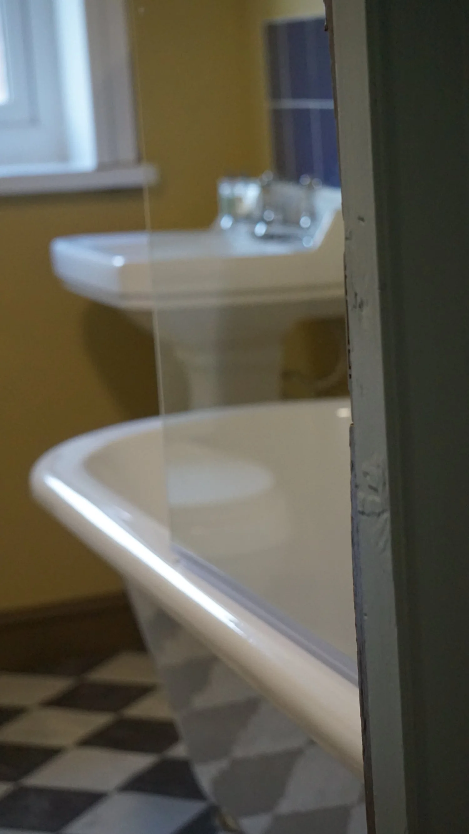 Close-up detail of a heritage bathroom with checkerboard floor tiles, freestanding bath and traditional basin, part of Stiwdio Interior Design’s Liverpool Georgian renovation.