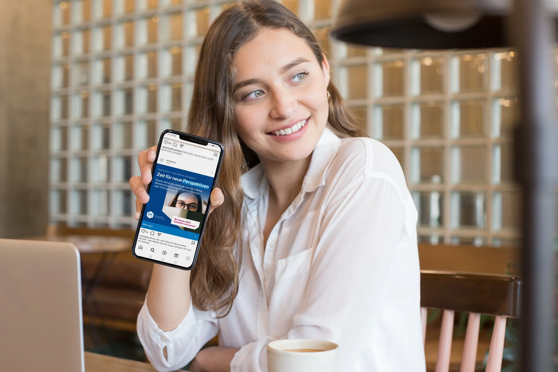 Junge Frau hält ein Smartphone in die Kamera und zeigt einen Social-Post