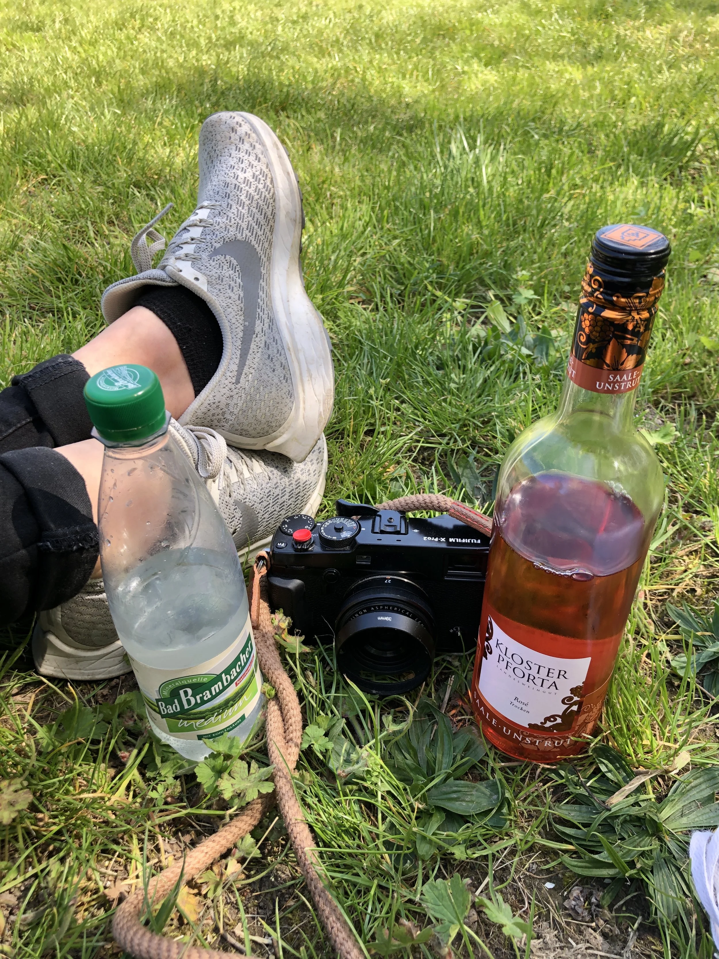 Eine Kamera neben einer Wein- und einer Wasserflasche.