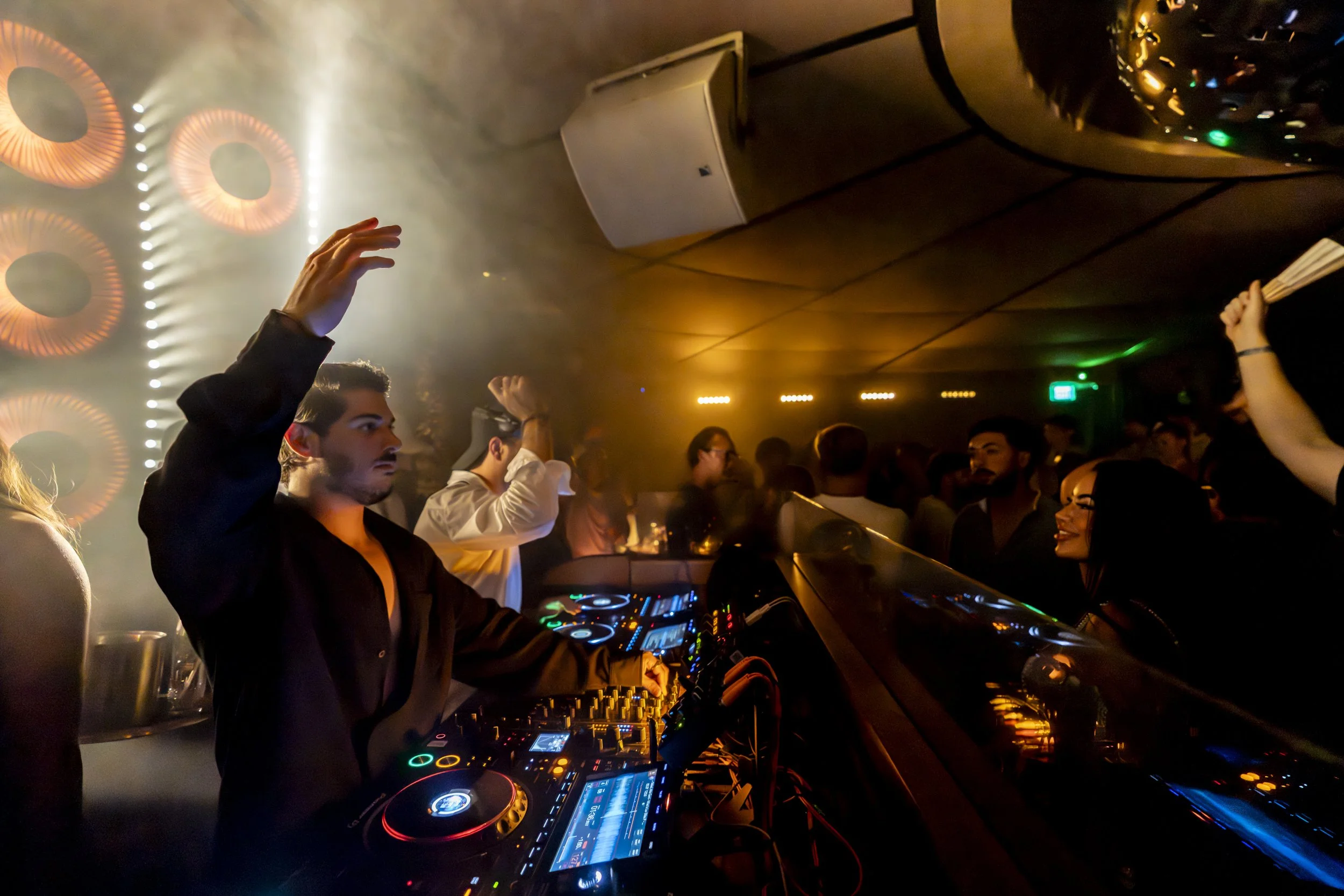Image of CASA NEOS Lounge, with people dancing and the DJ playing music.