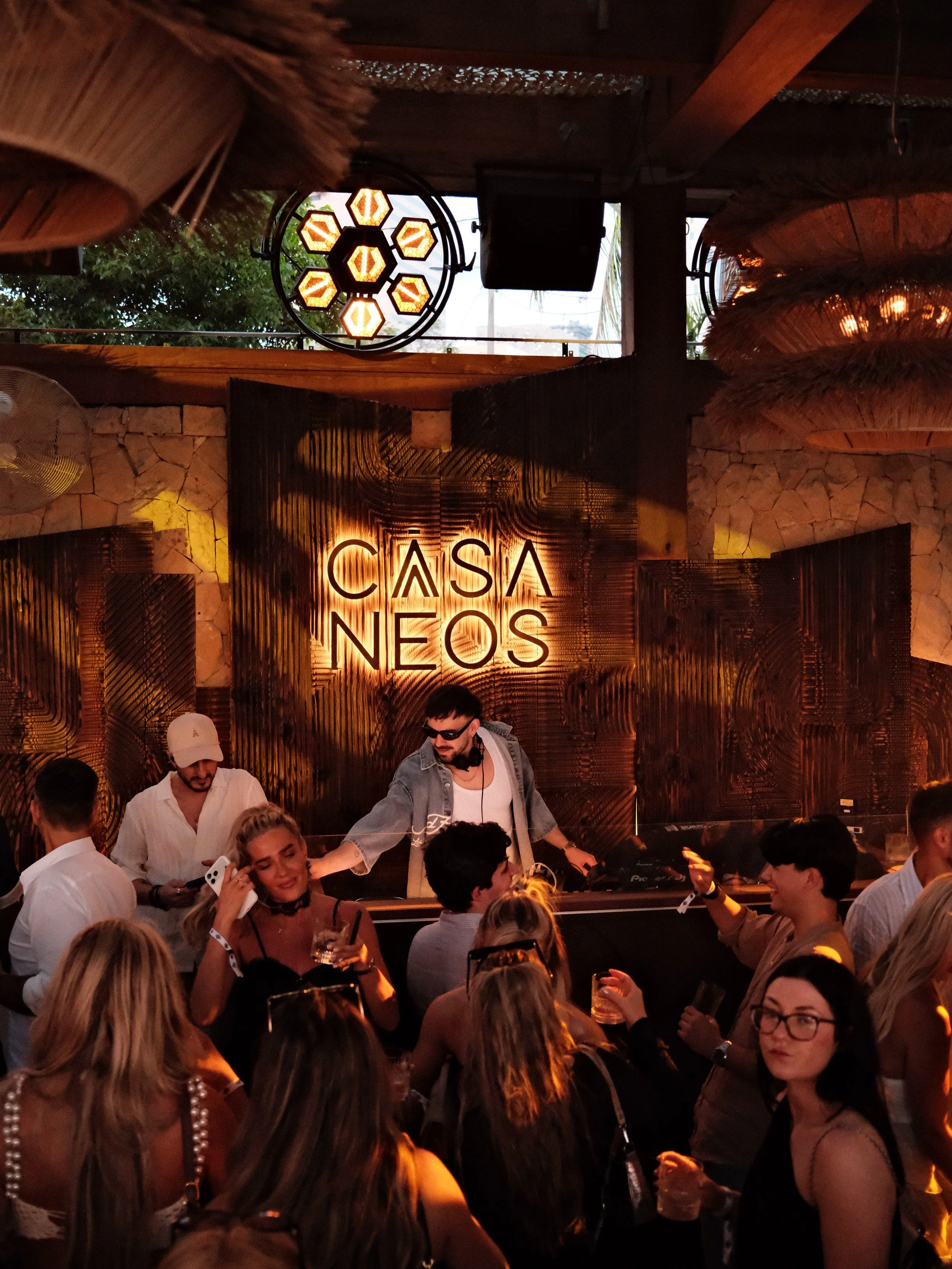 Image of a DJ performing at CASA NEOS beach club during sunset rituals, on the weekend.
