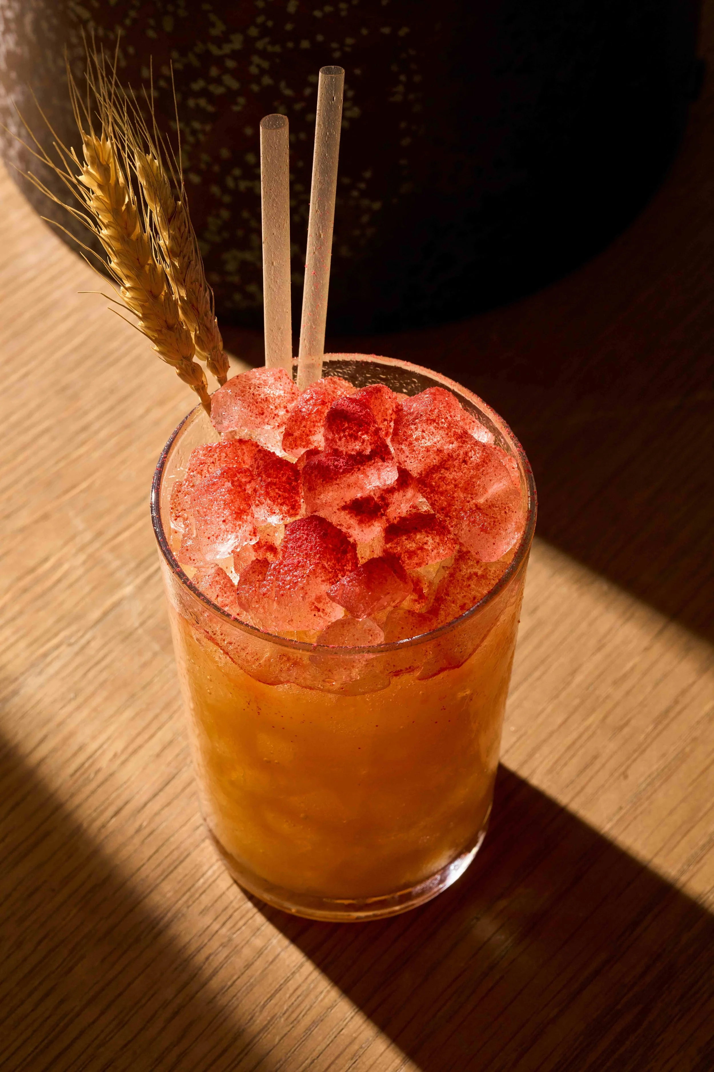 A refreshing organge cocktail with red seasoning on top of the ice.