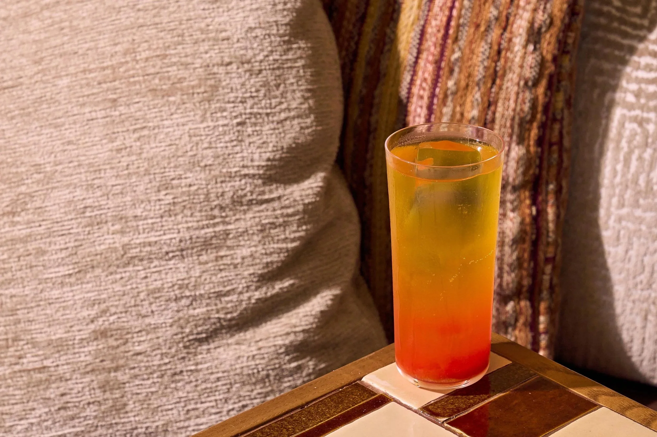 A refreshing orange gradient cocktail, that is on a table in the Members-only rooftop.