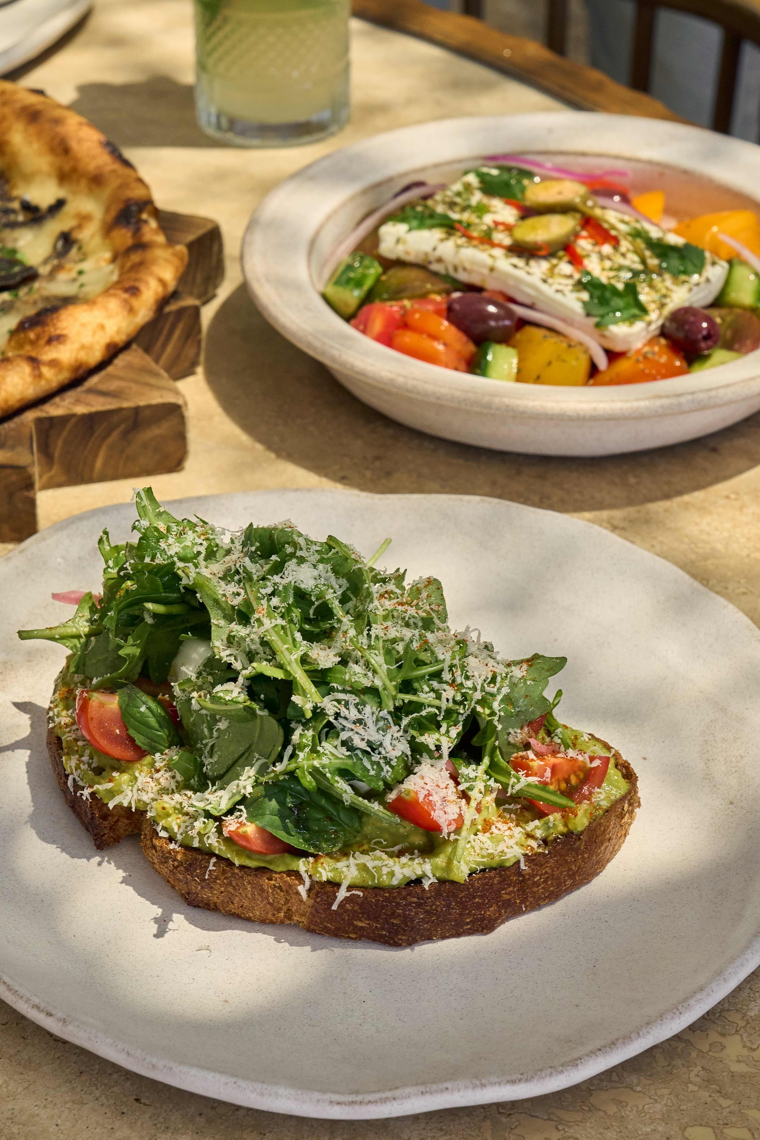 Avocado toast with spinach, tomato and cheese on top, with a side of greek salad served at CASA NEOS brunch.