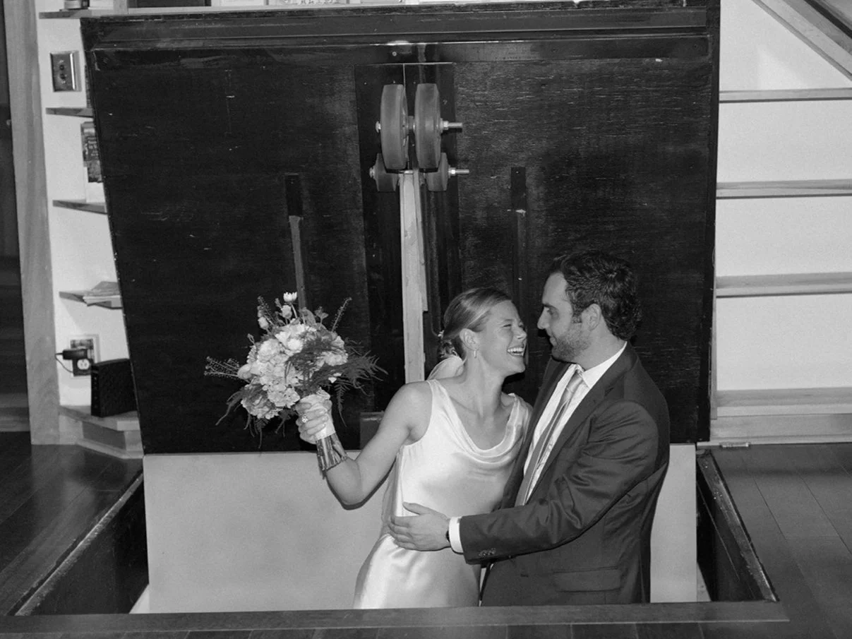 A bride and groom sharing a joyful moment, with the bride holding a bouquet of flowers, in a wedding celebration setting.