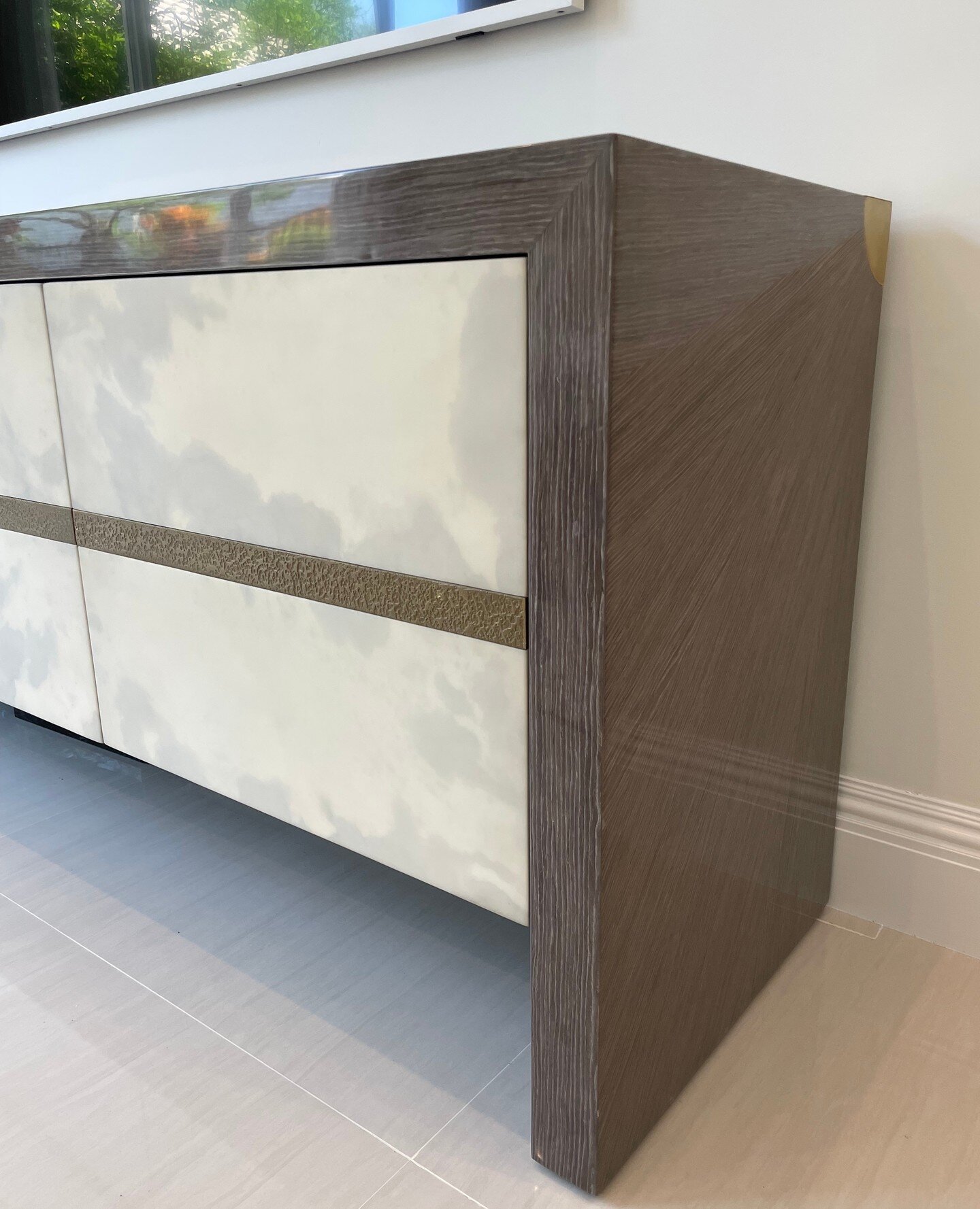 Corner view of a custom high gloss 3-door sideboard with textured bronze detailing. #PGD ⁠