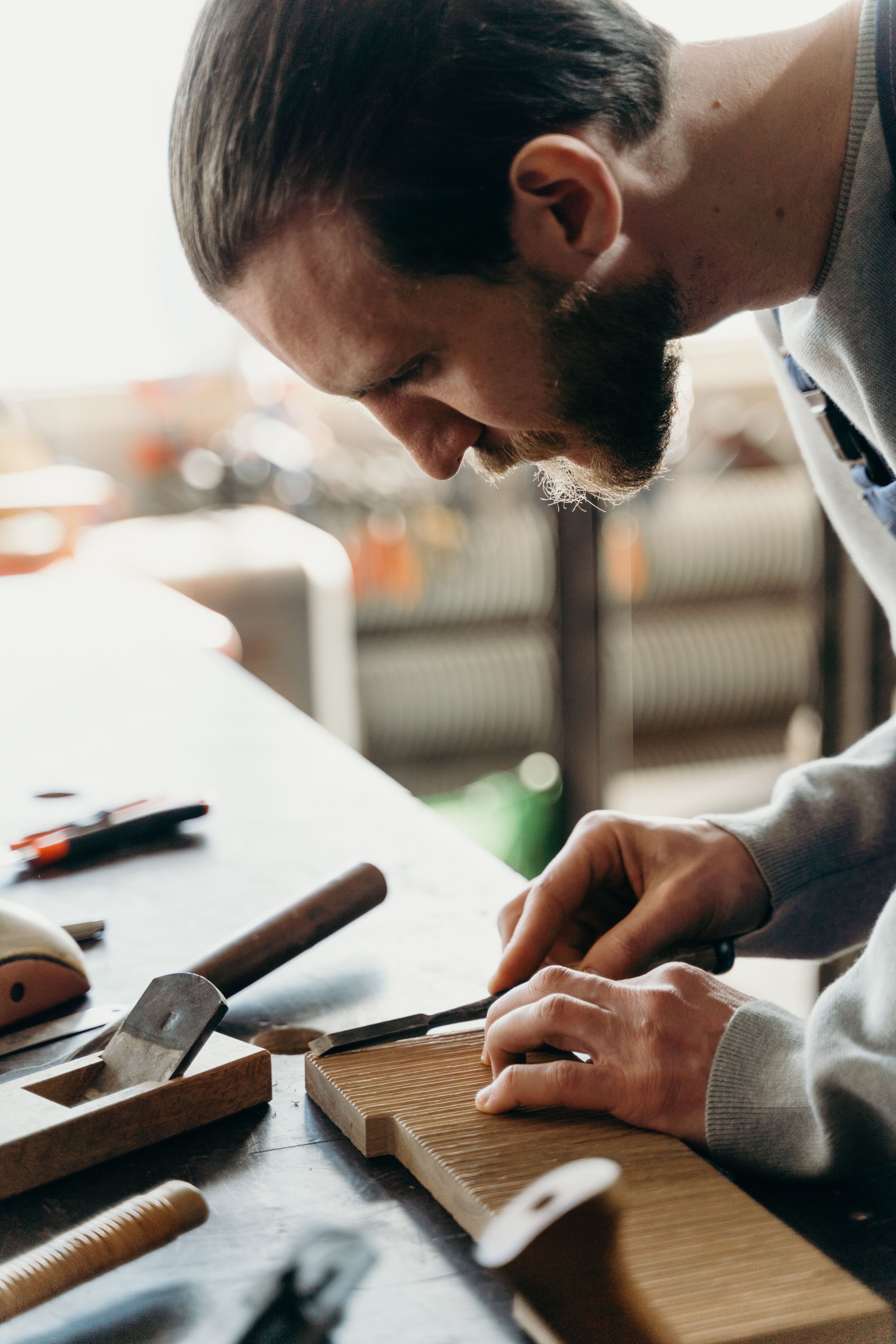 A man with dark hair and a beard working with woodworking tools on a project at a workbench. Individual Therapy in Toronto