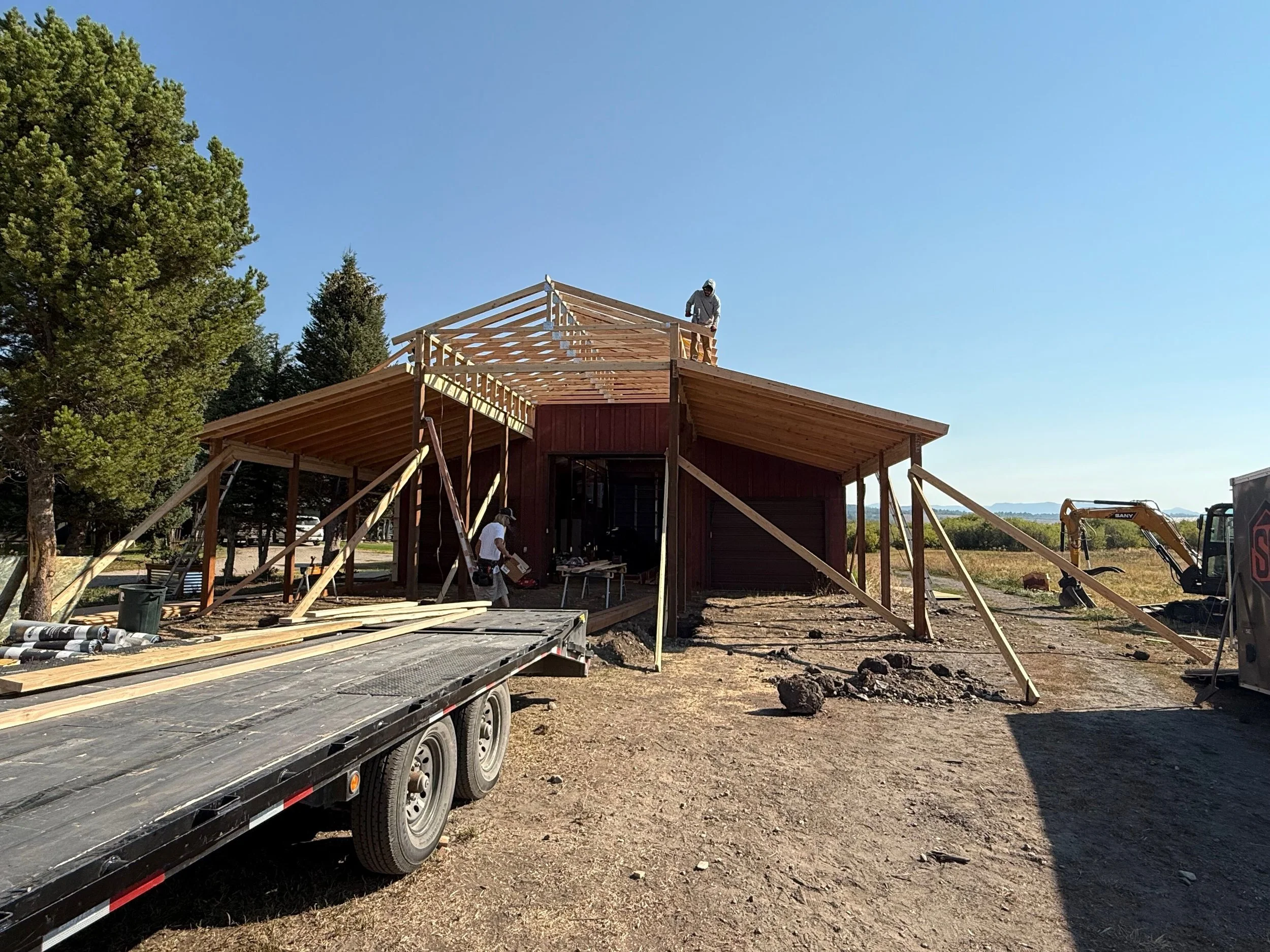 Construction workers building a house with a wooden frame on a clear, sunny day.