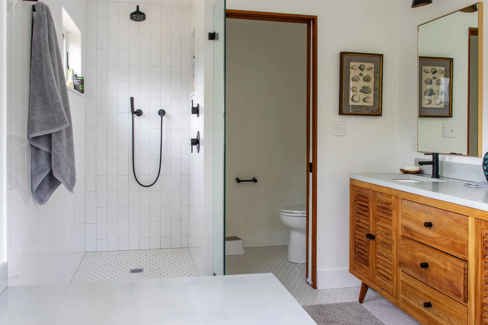 custom bathroom with white tile and black fixtures and wood vanity