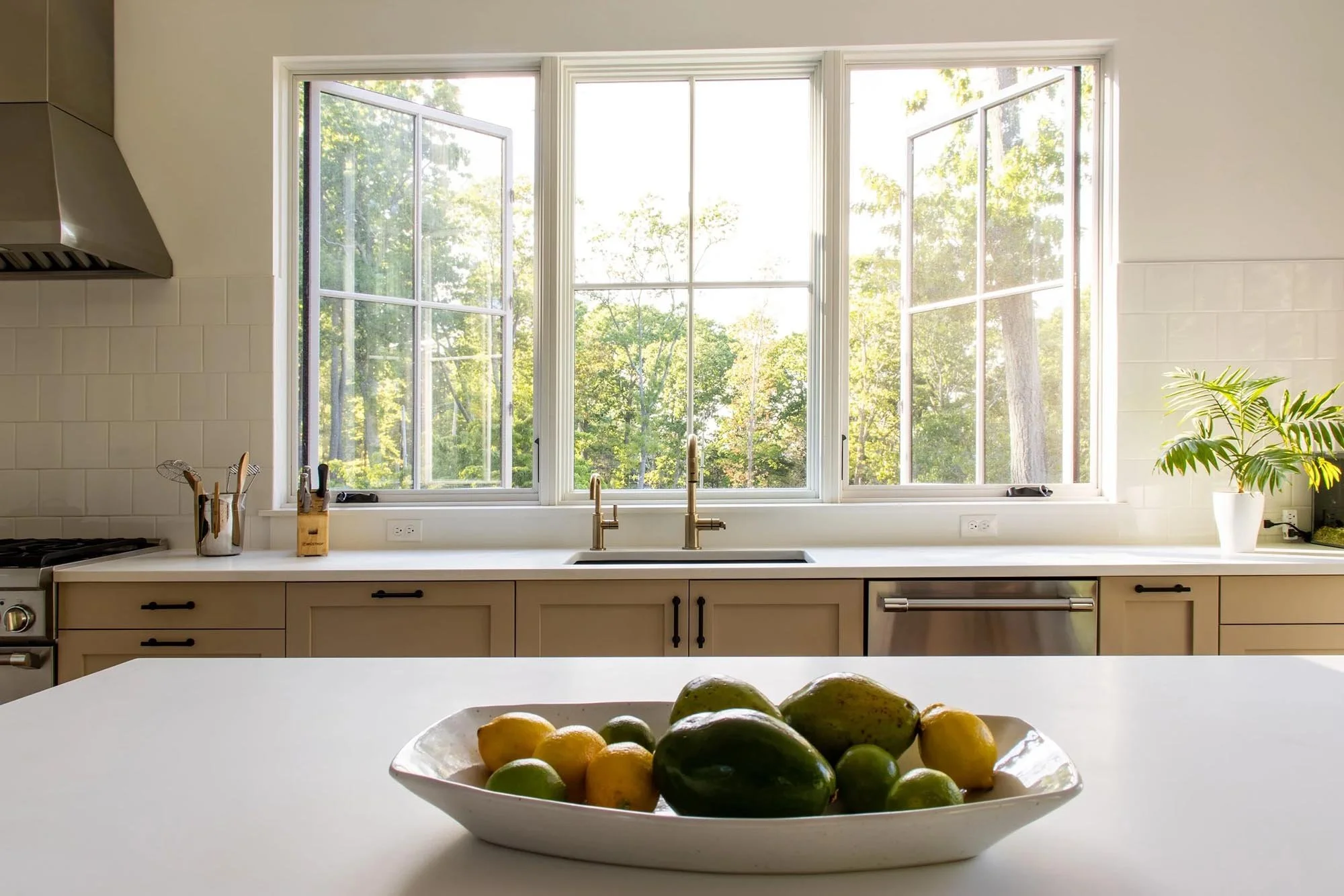 kitchen with big casement windows in front of sink with white tile backsplash and countertops