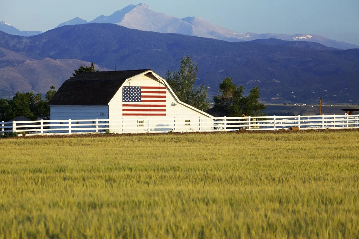 Barn rested in rural setting with a large U.S.A. flag on it
