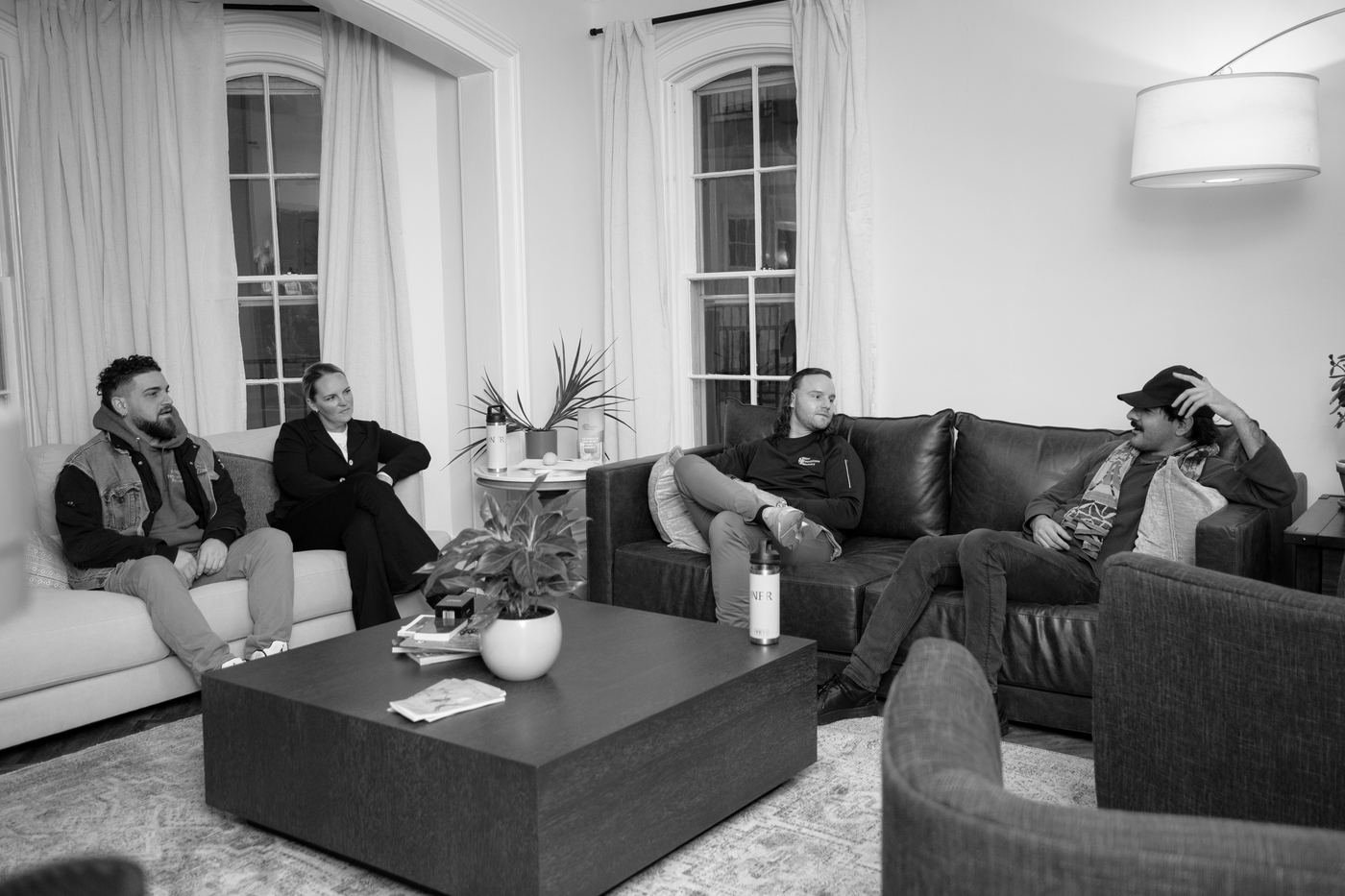 A peer coaching session in progress at the NFR office — four people seated around a coffee table in a warm, home-like living room.