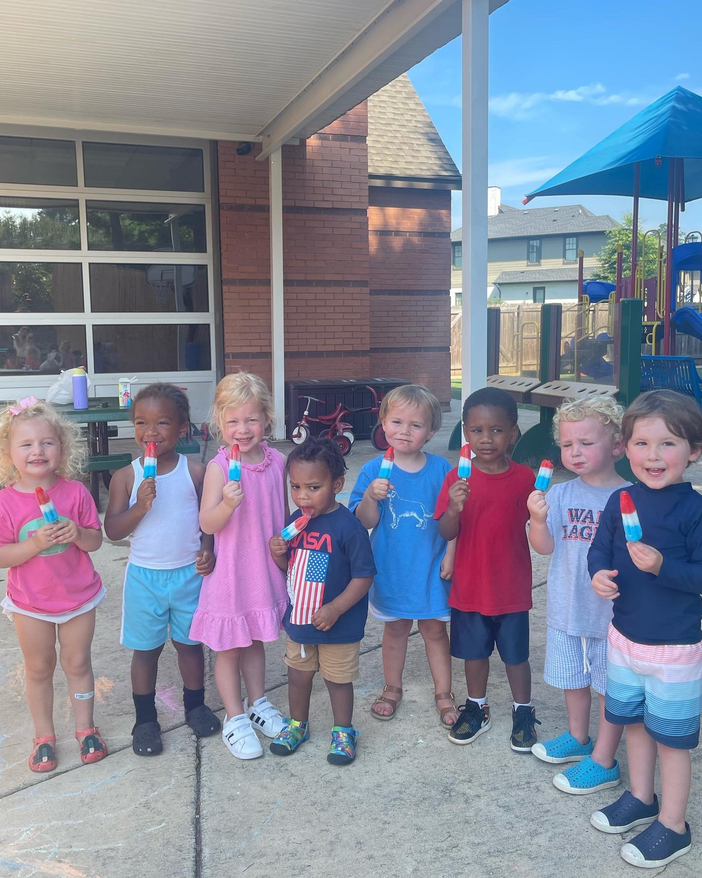 Preschool campers eating popsicles outside.