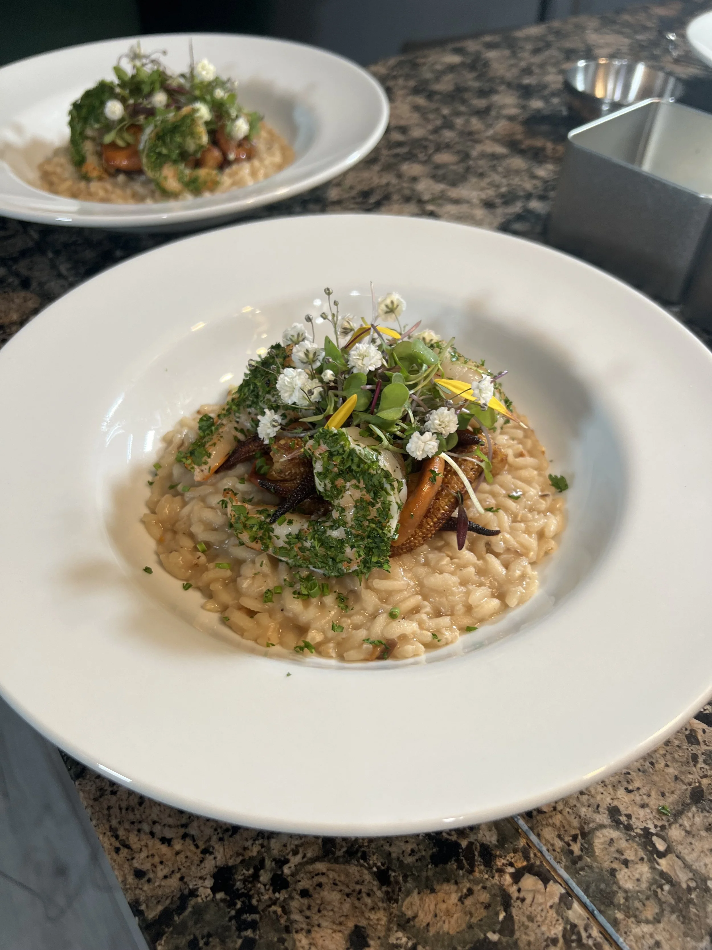 A plate of creamy risotto garnished with microgreens and edible flowers.
