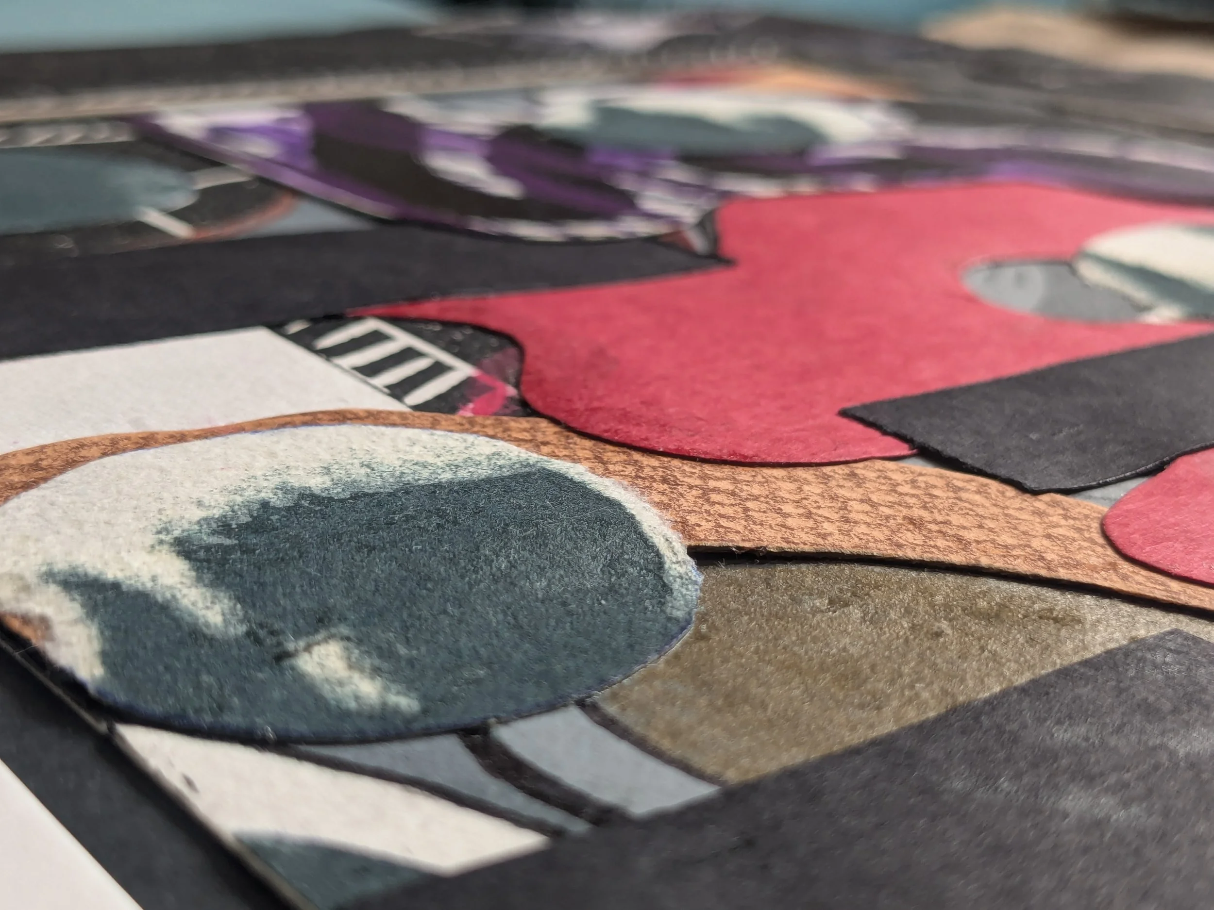 Close-up view of a textured collage with various paper cutouts in red, black, white, teal, and brown, arranged abstractly.