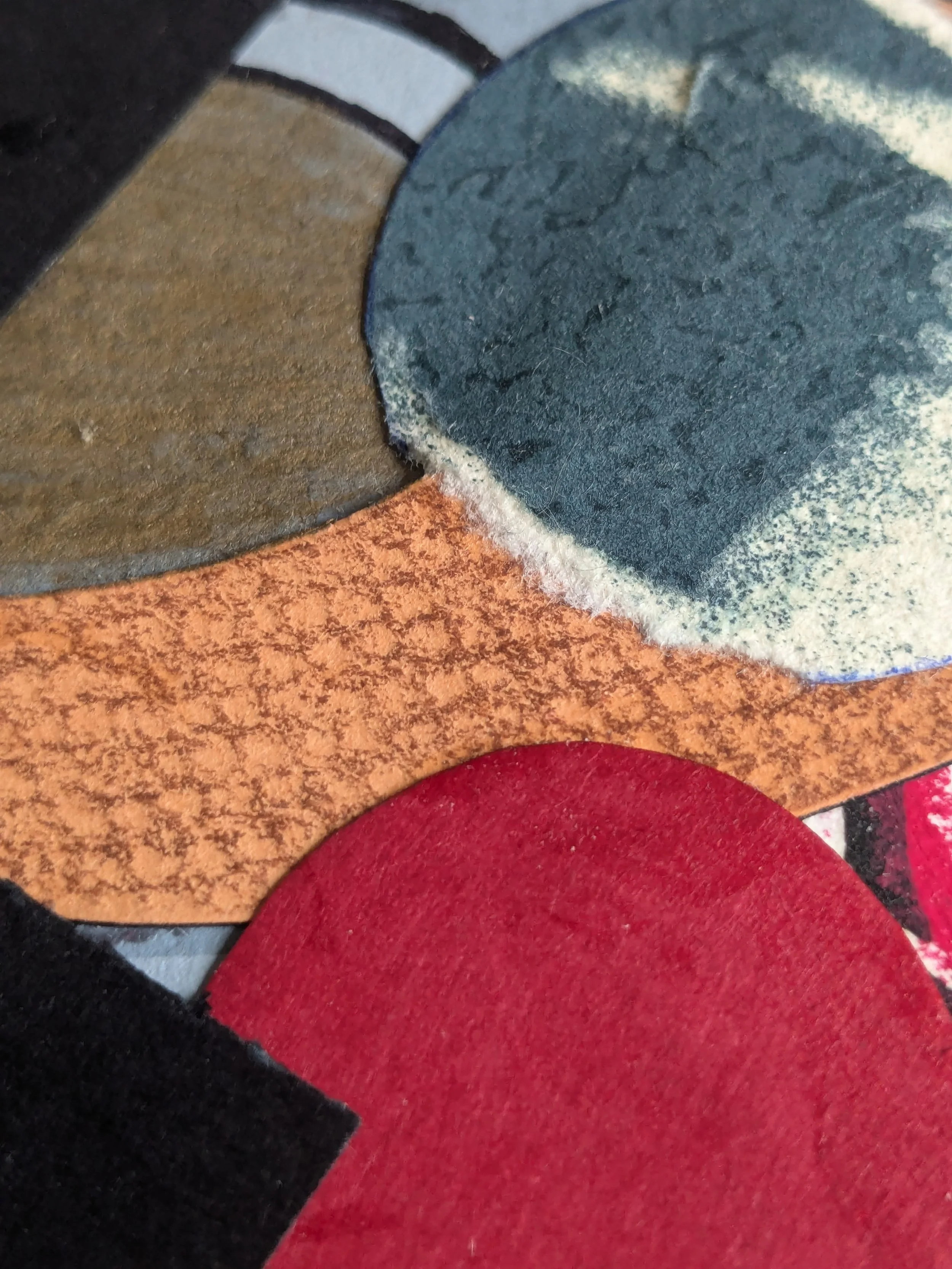 Close-up of multicolored paper with multiple textures, including black, brown, blue, red, orange, and pink sections.