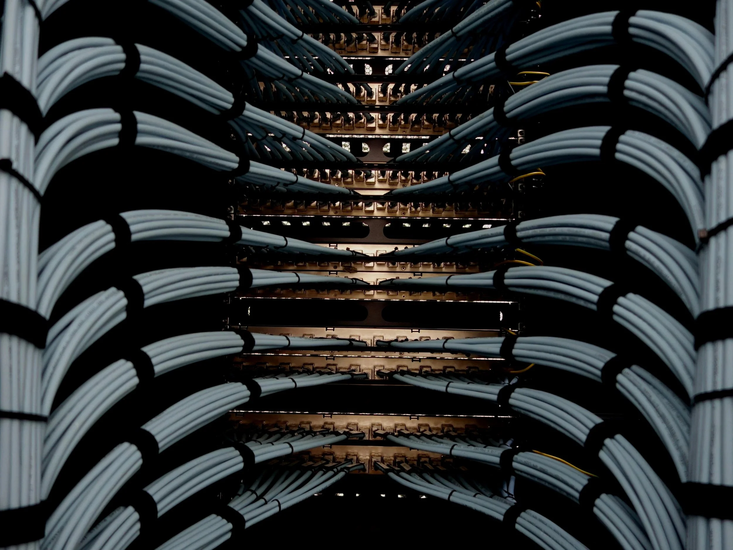 A close-up view of a large electrical infrastructure with neatly organized white cables connected to a metallic rack.