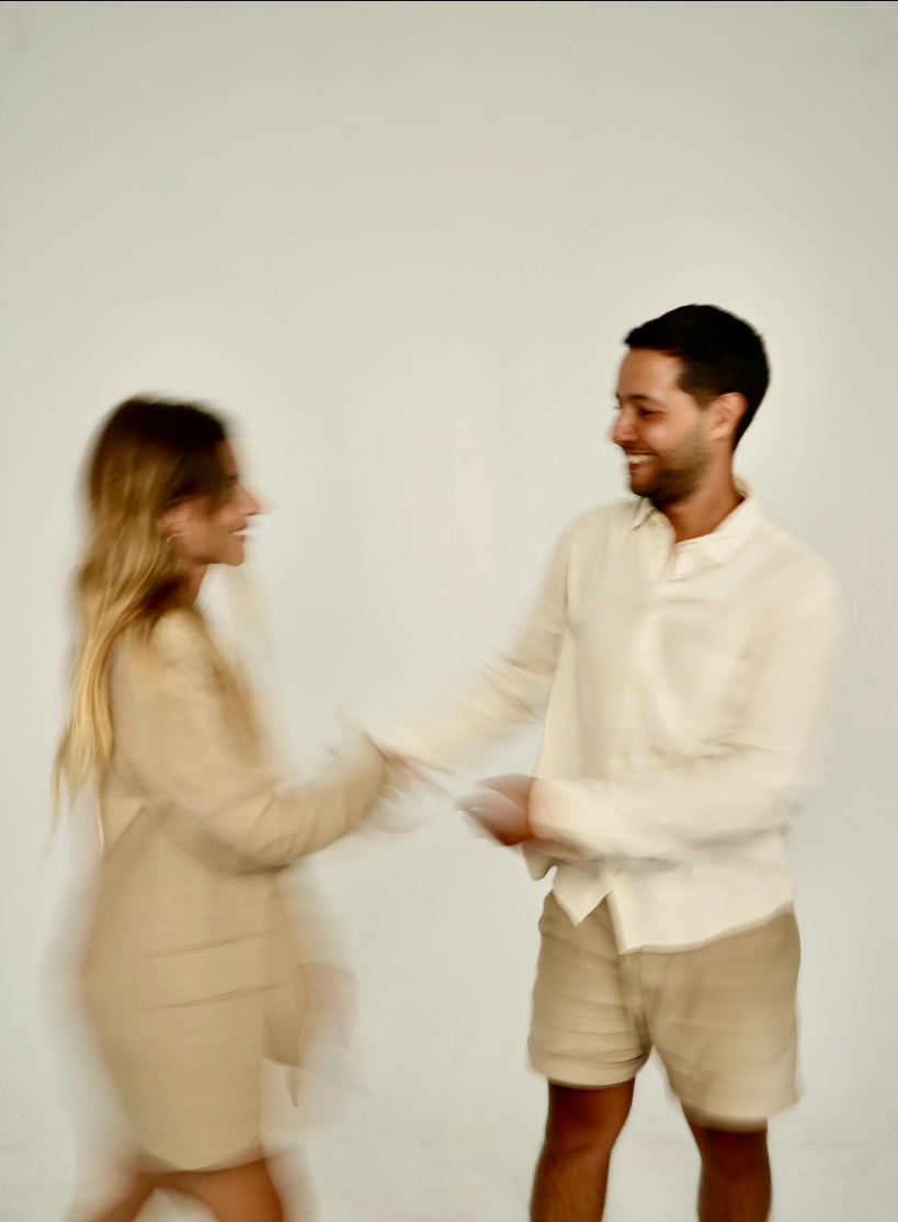 A blurry photo of a happy man and woman holding hands and smiling at each other against a plain white background.