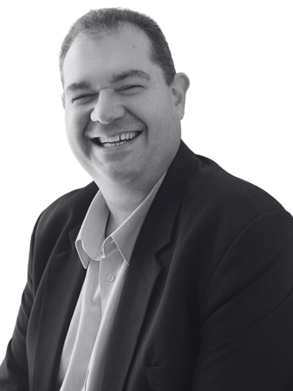 A black and white portrait Michael Gershkov, dressed in a suit and open shirt.