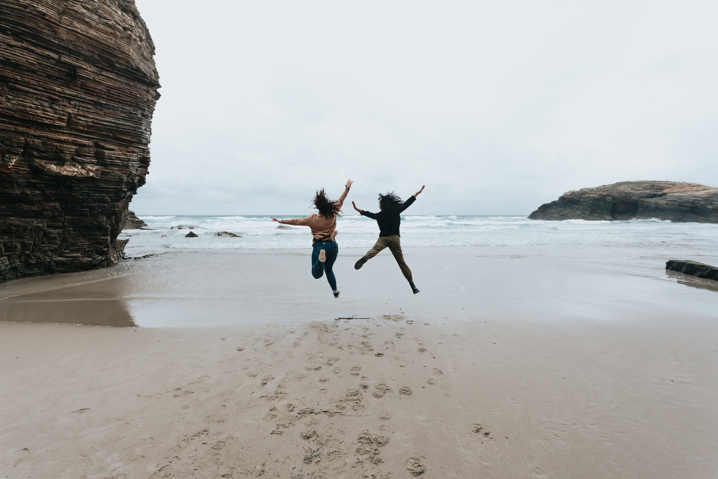 two-people-jump-high-on-a-sandy-beach.jpg