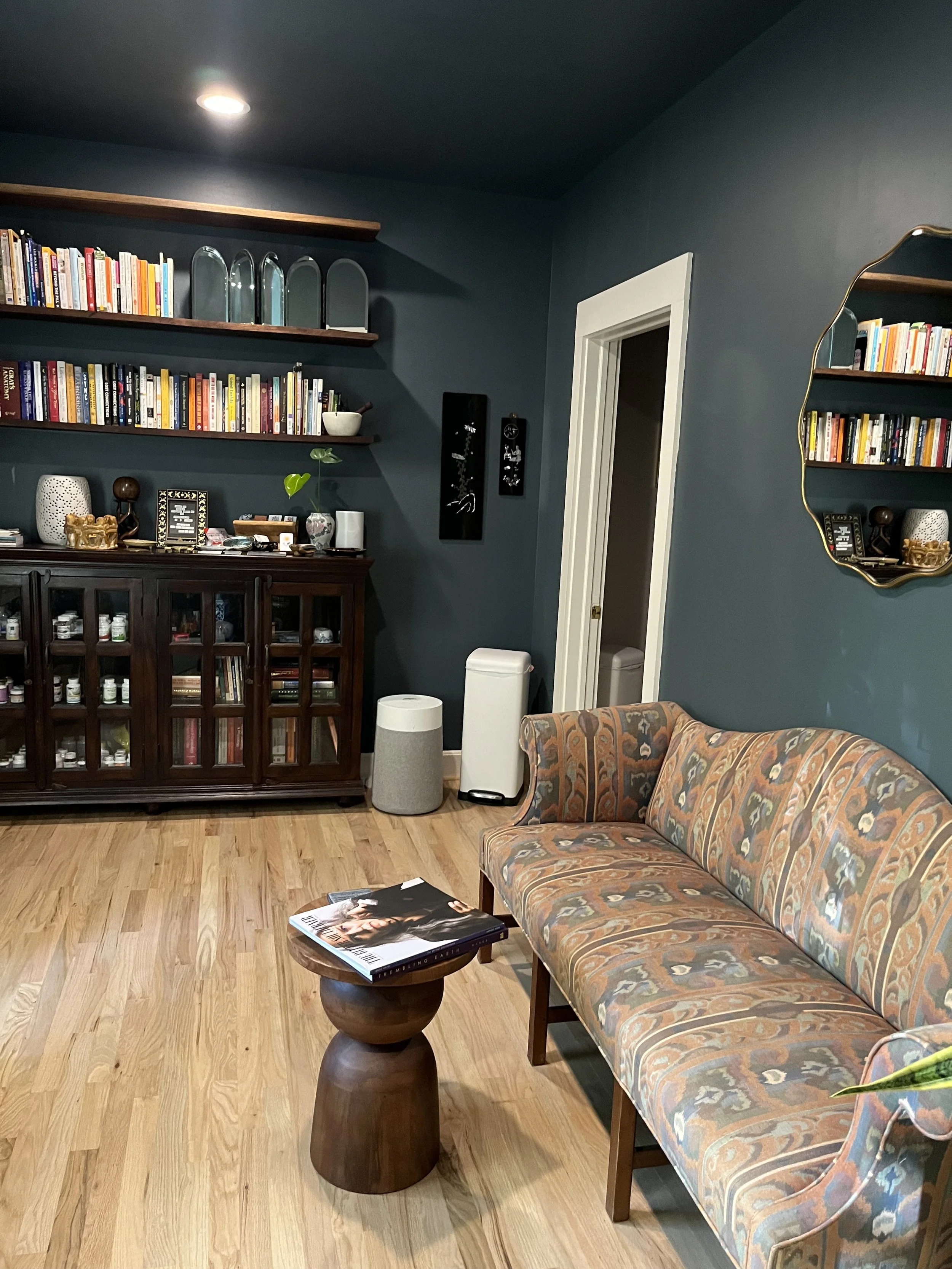 Peaceful waiting area at Taproot Counseling. There is soft lighting, comfortable seating, and tasteful decor. The waiting area is shared with Sacred Sea Acupuncture + Herbal Medicine.