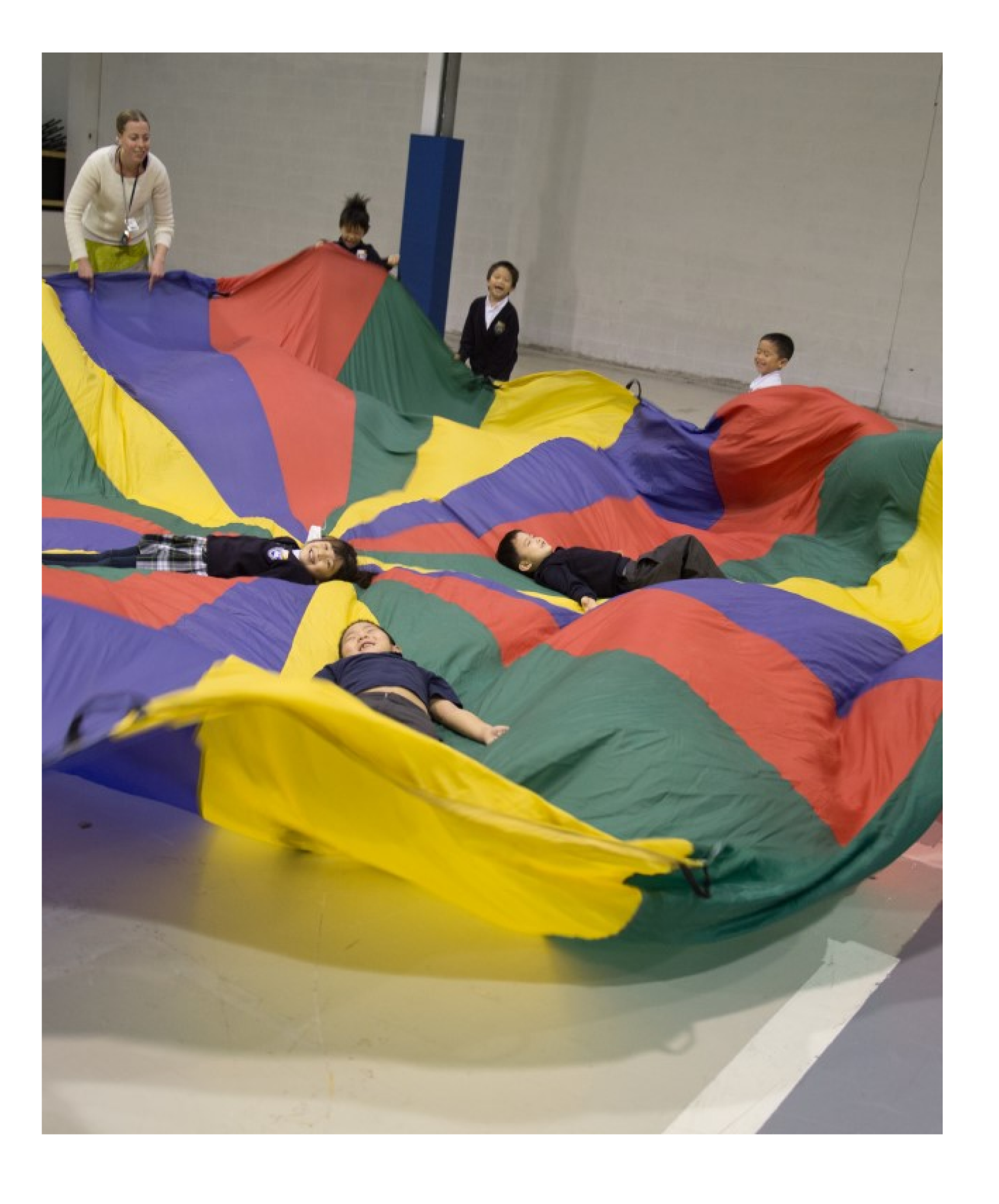 Children playing with a gigantic rainbow coloured parachute