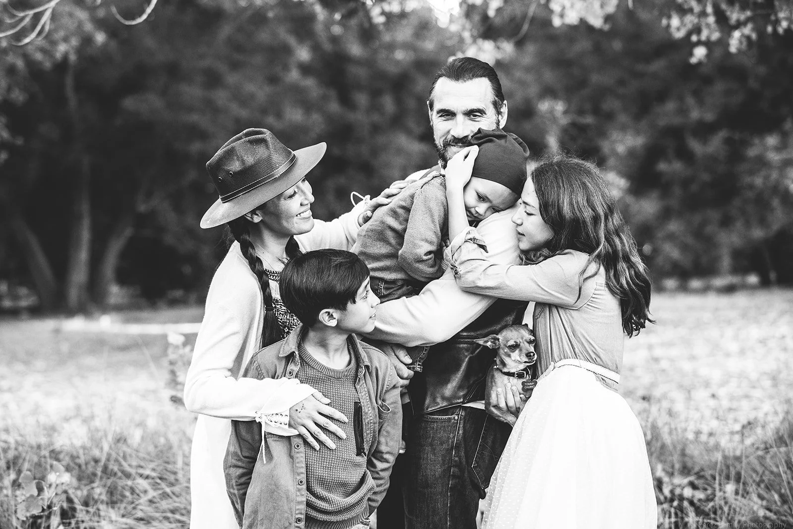 Unposed family portraits in Littleton with parents walking hand-in-hand with children at sunset.